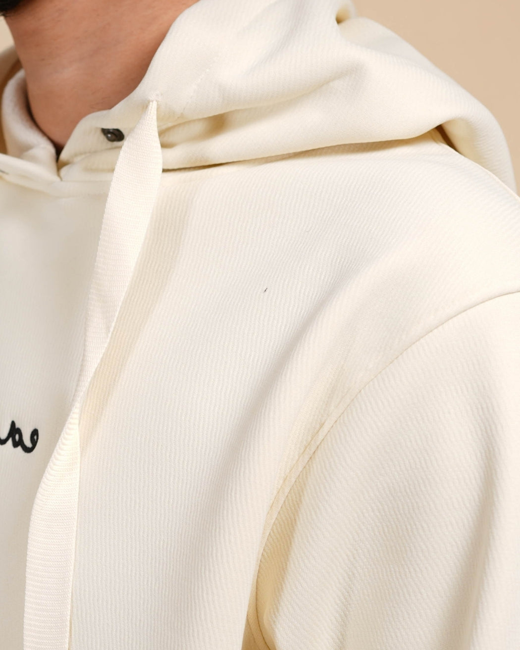 Close-up of a person wearing a white hoodie with a brand logo on the chest.