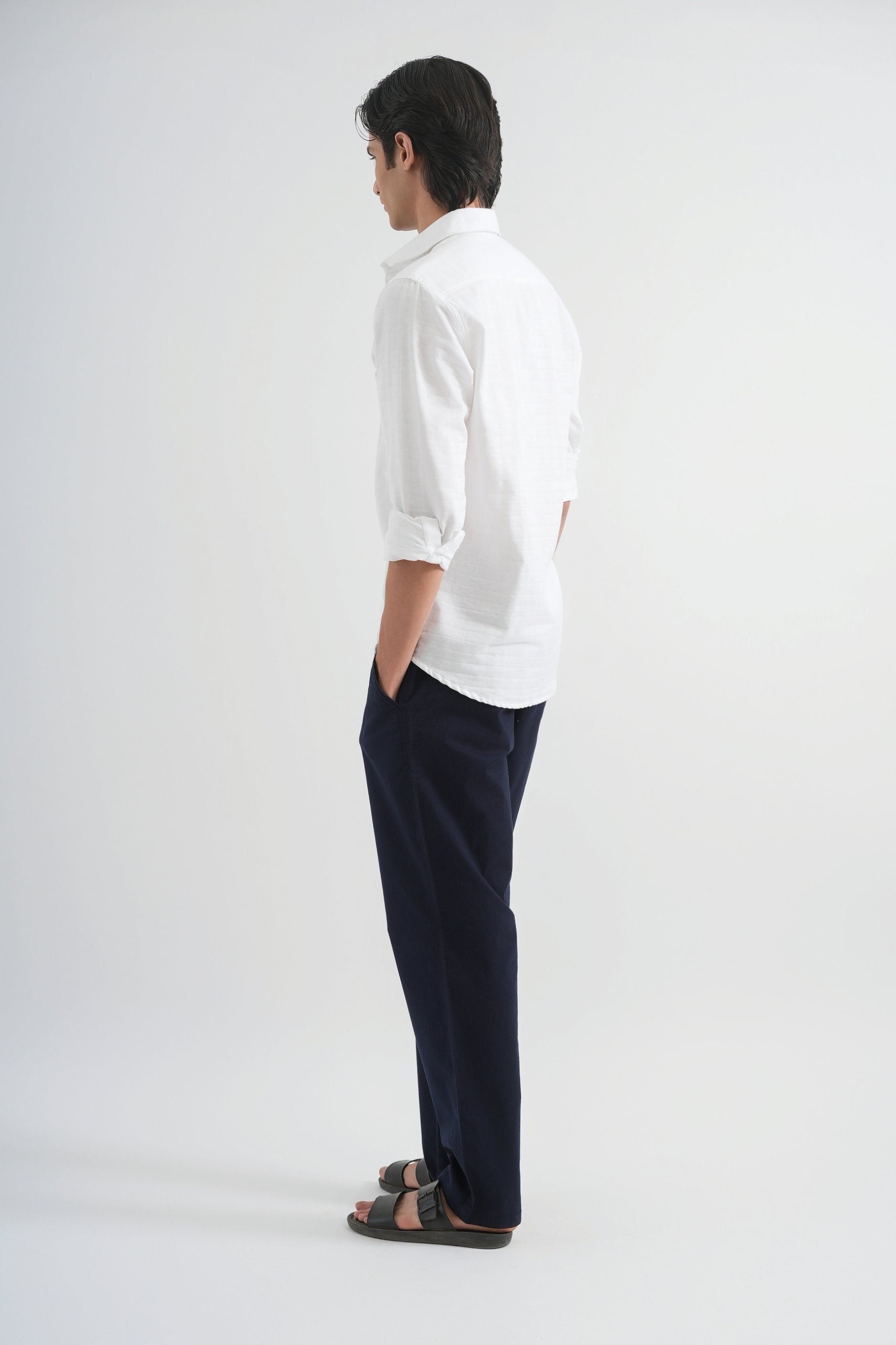 Person wearing a white shirt and dark pants on a white background