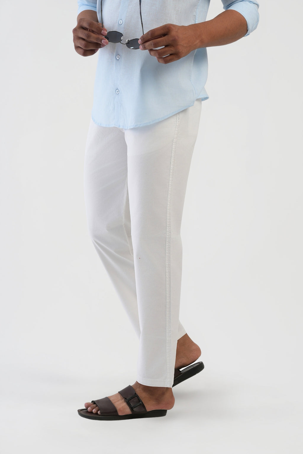 Person wearing a light blue shirt and white pants on a white background