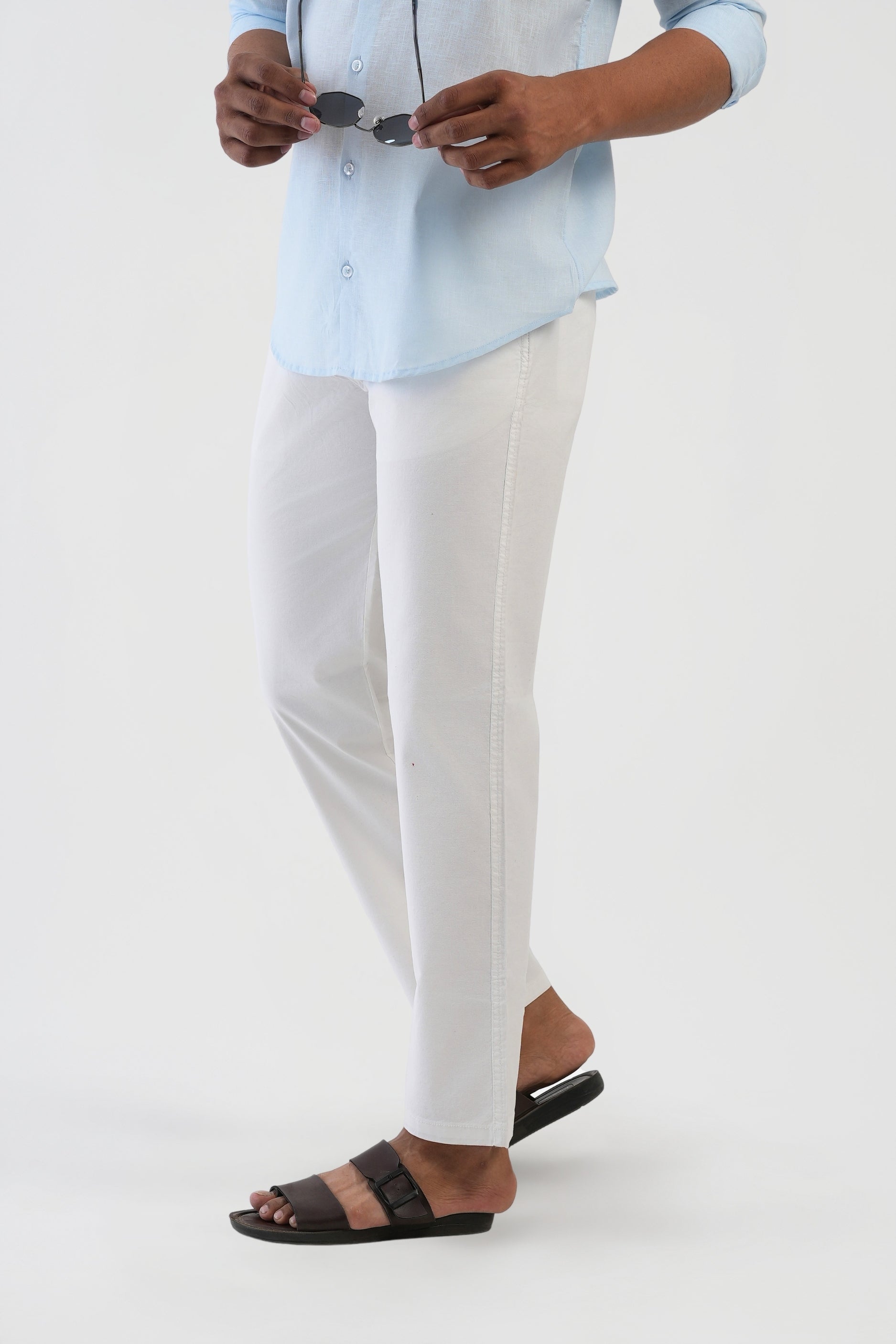 Person wearing a light blue shirt and white pants on a white background