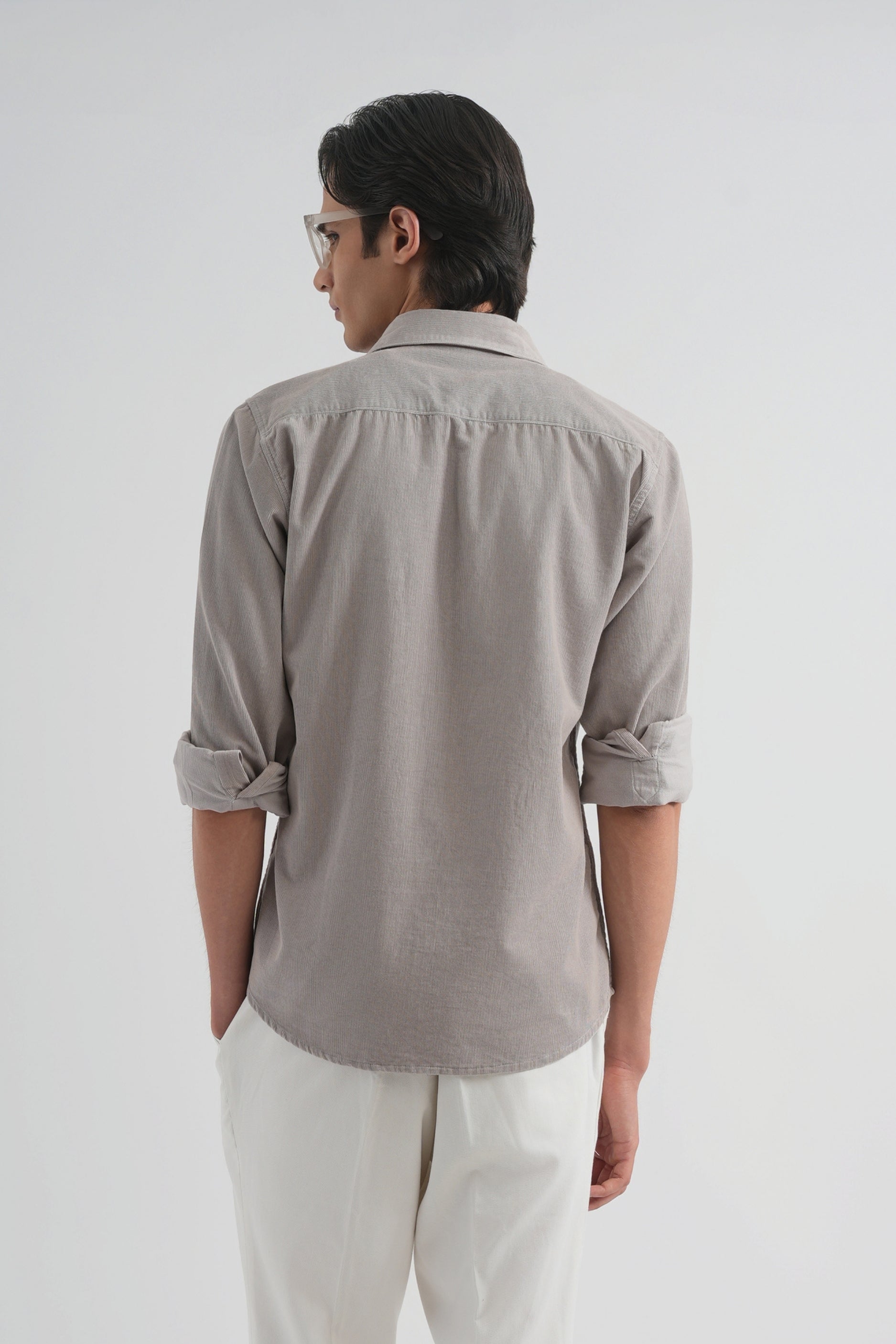 Man wearing a gray shirt and white pants on a white background