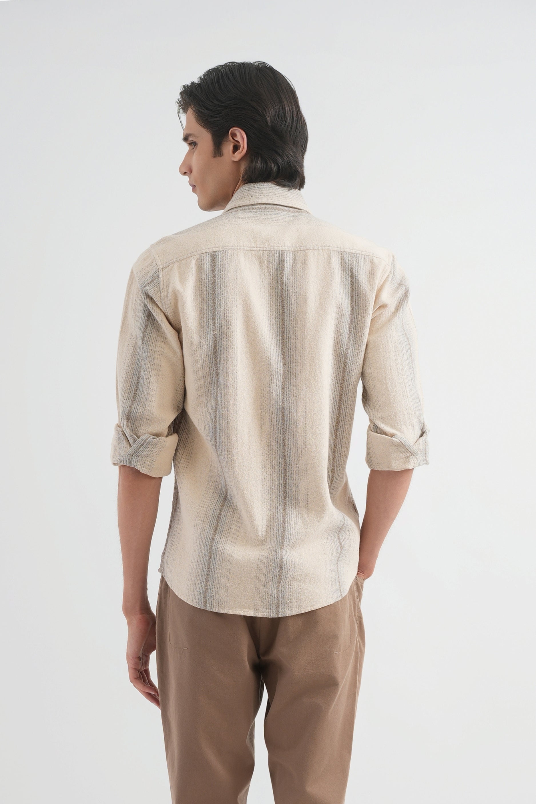 Man wearing a beige striped shirt and brown pants on a white background