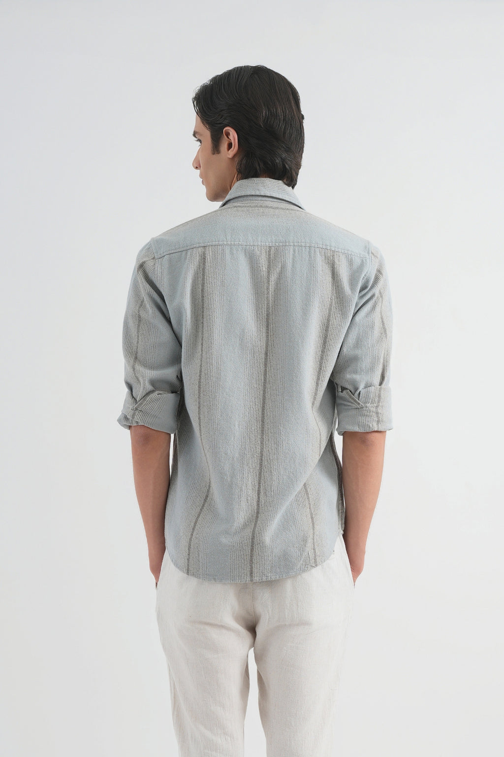 Man wearing a light gray checkered shirt and white pants on a white background