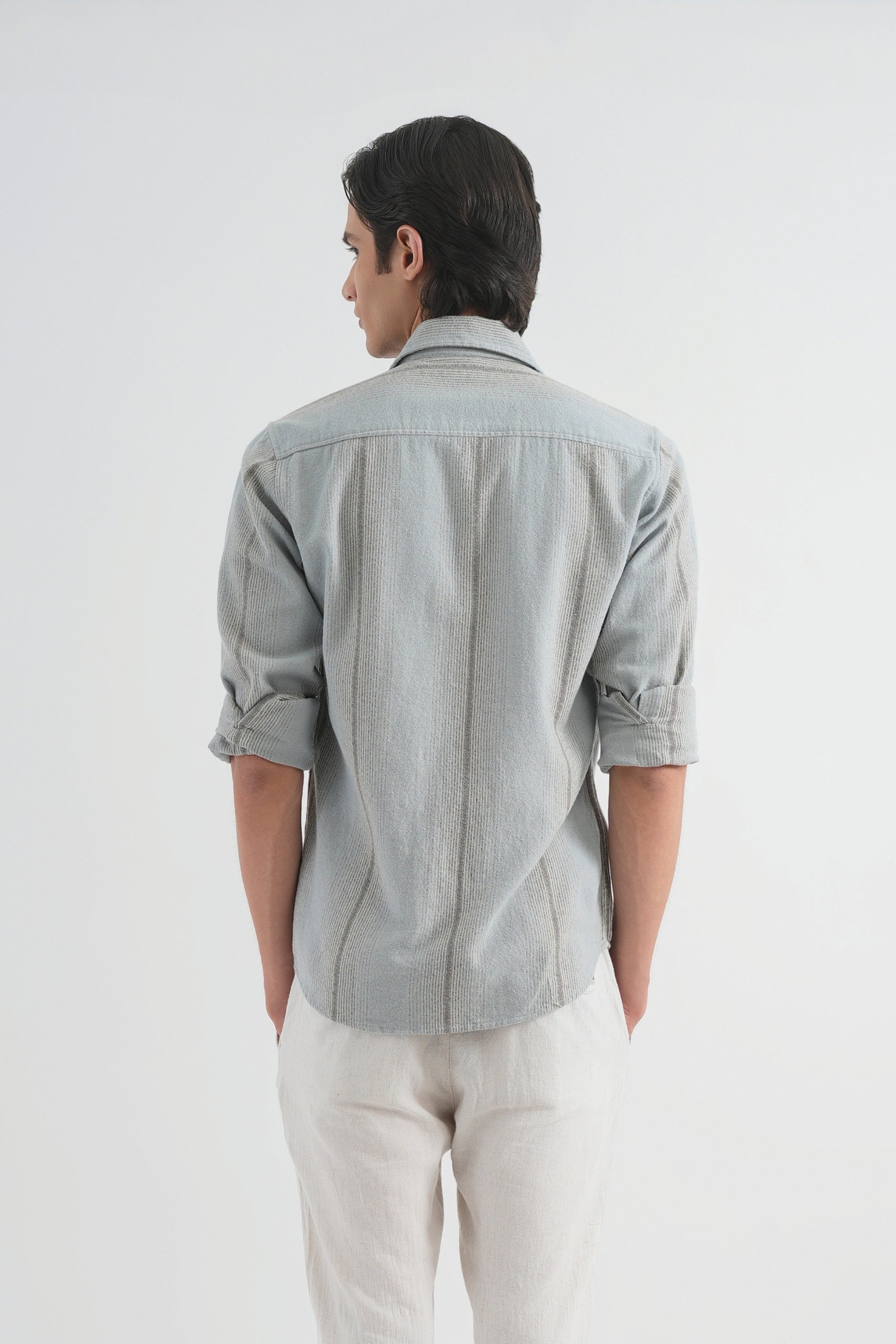 Man wearing a light gray checkered shirt and white pants on a white background