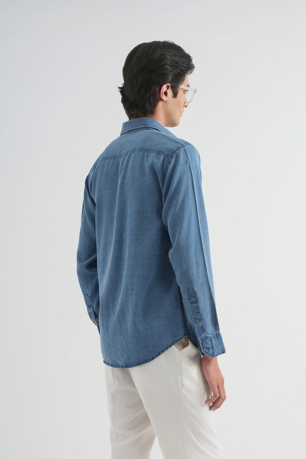 Person wearing a blue shirt and white pants on a white background