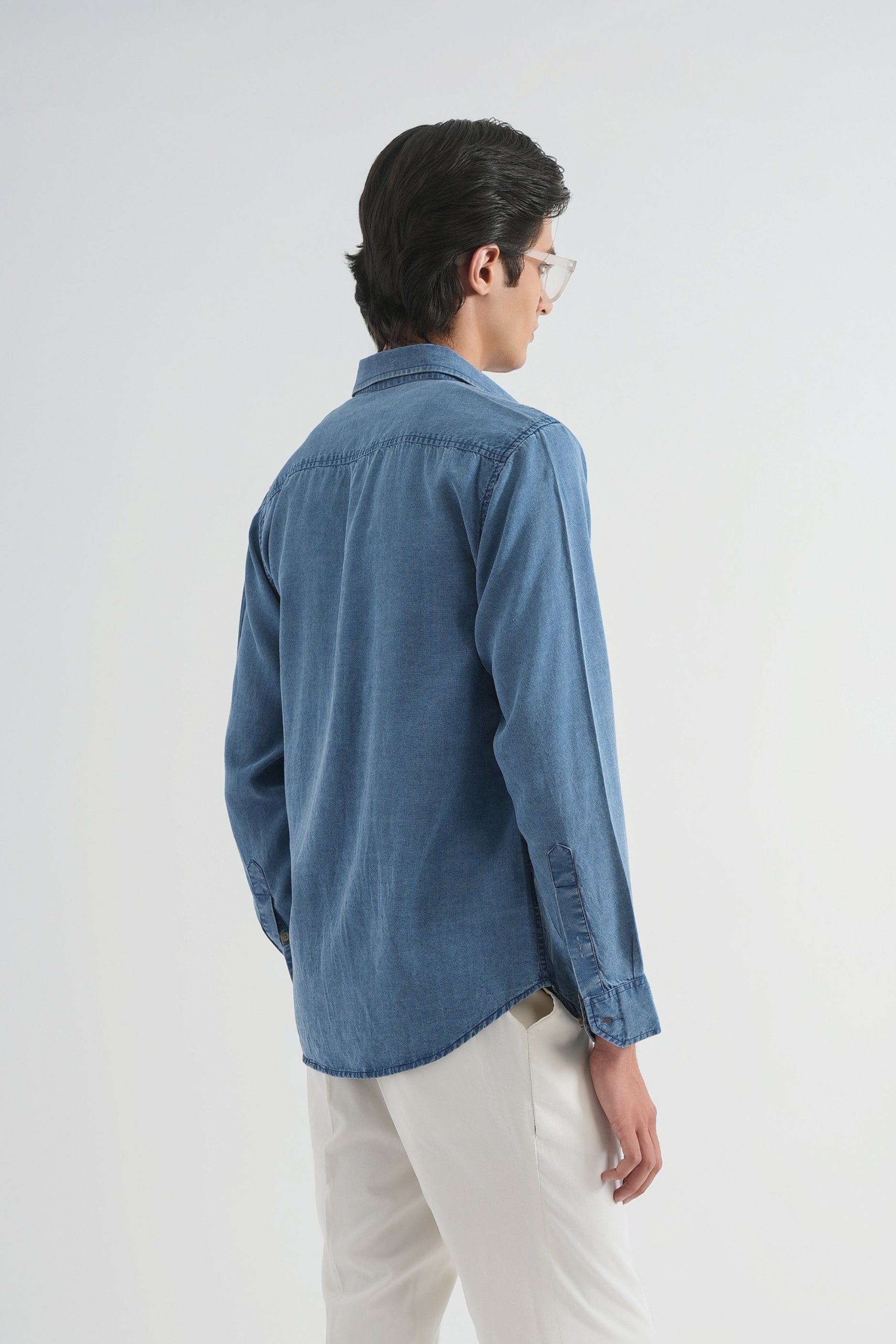 Person wearing a blue shirt and white pants on a white background