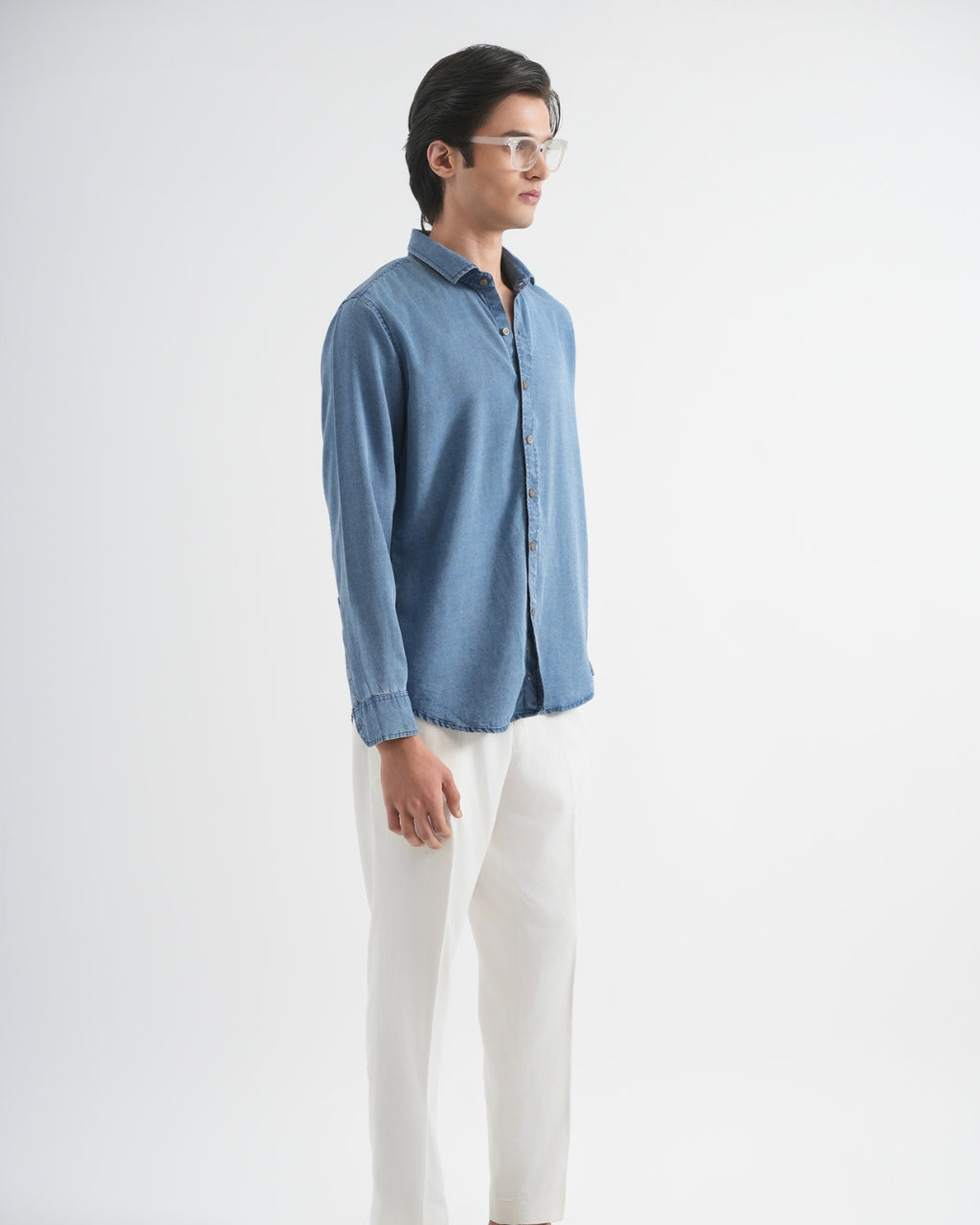 Man wearing a blue shirt and white pants on a white background