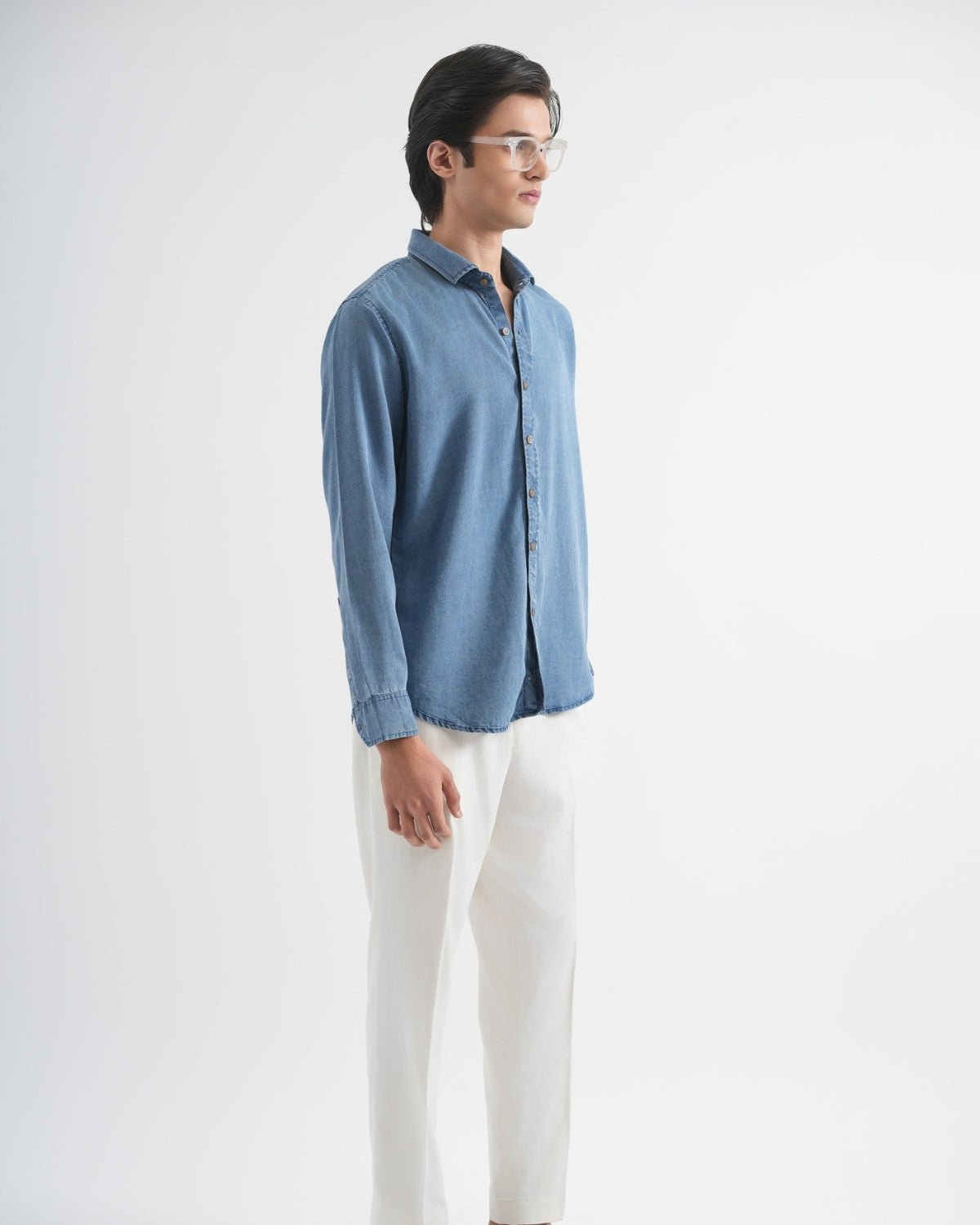 Man wearing a blue shirt and white pants on a white background