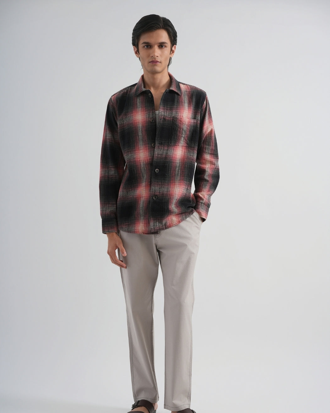 Man wearing a plaid shirt and light-colored pants on a white background