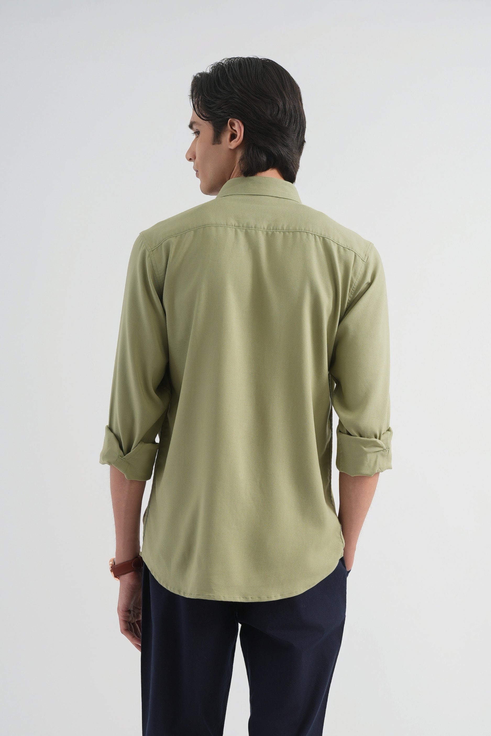 Man wearing a light green shirt and dark blue pants on a white background