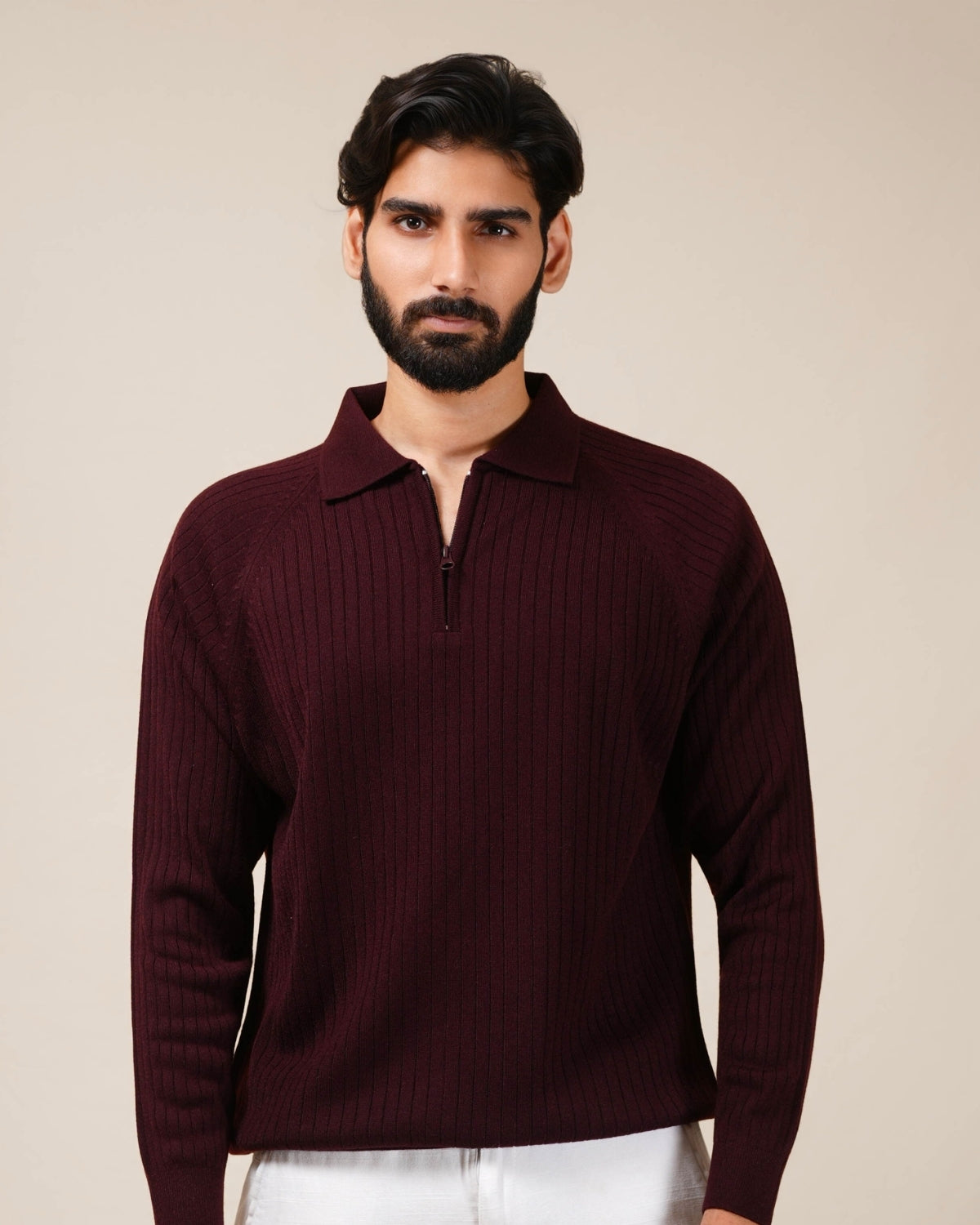 Man wearing a burgundy ribbed sweater against a beige background