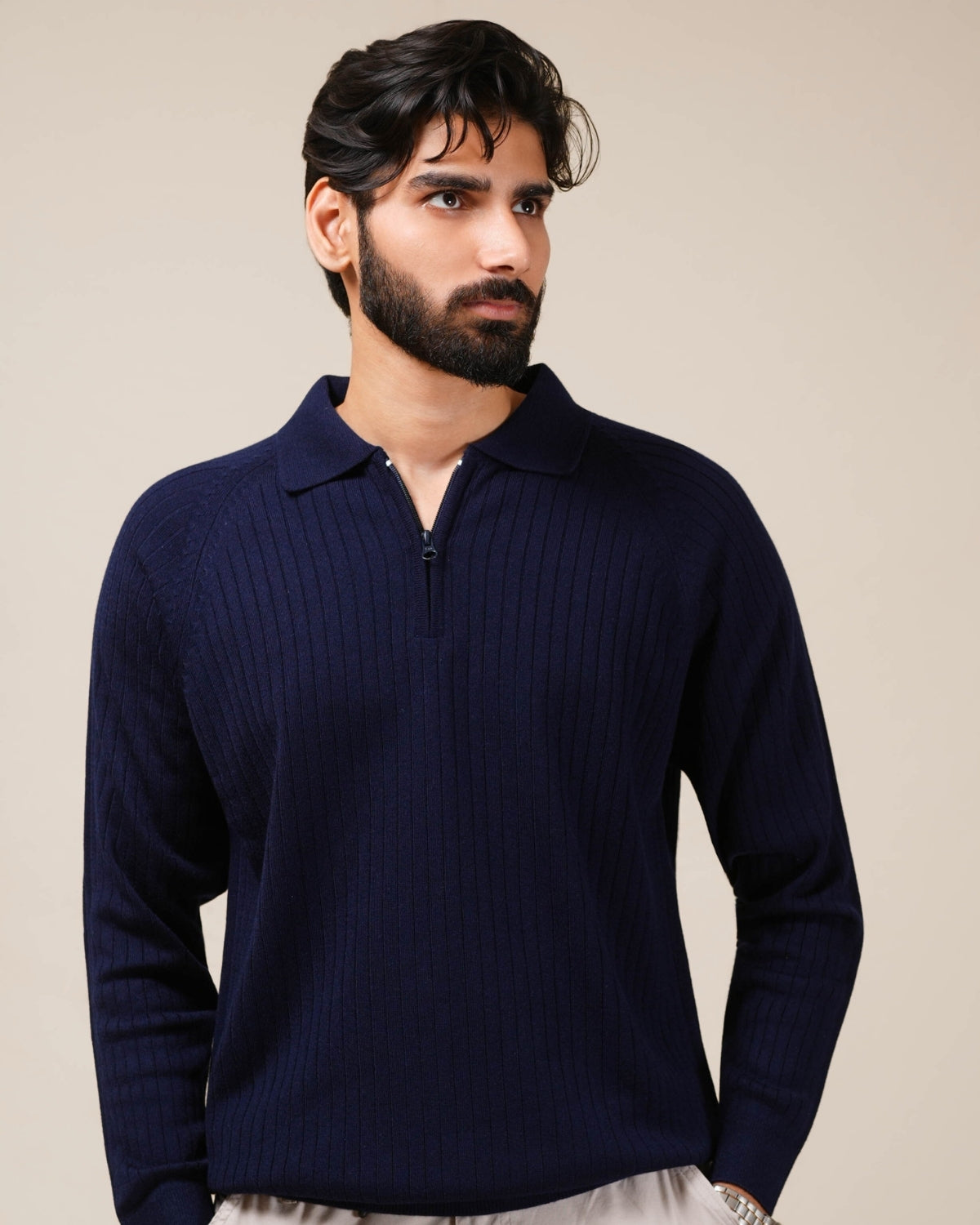 Man wearing a navy blue sweater against a beige background