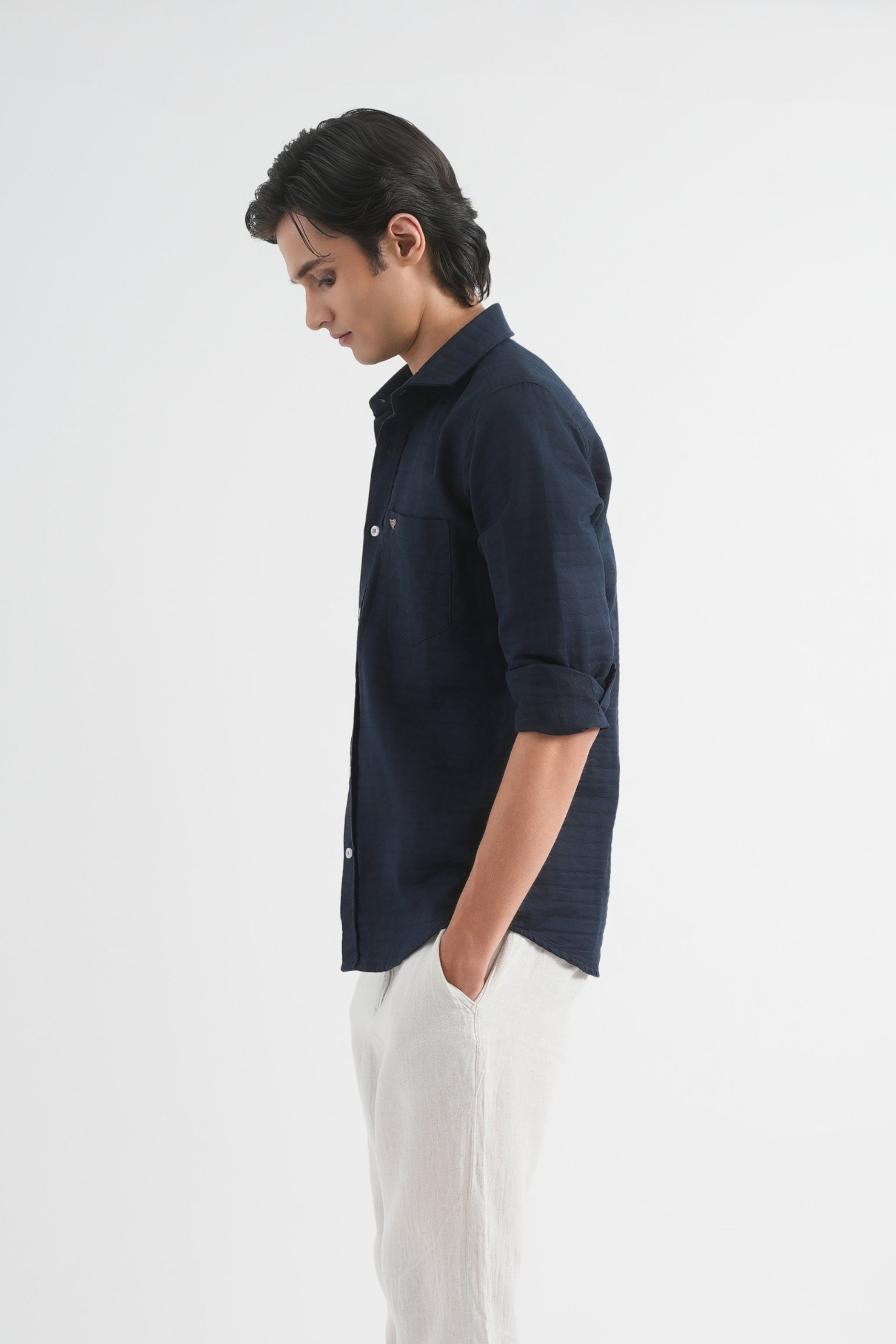 Man wearing a navy shirt and white pants on a white background