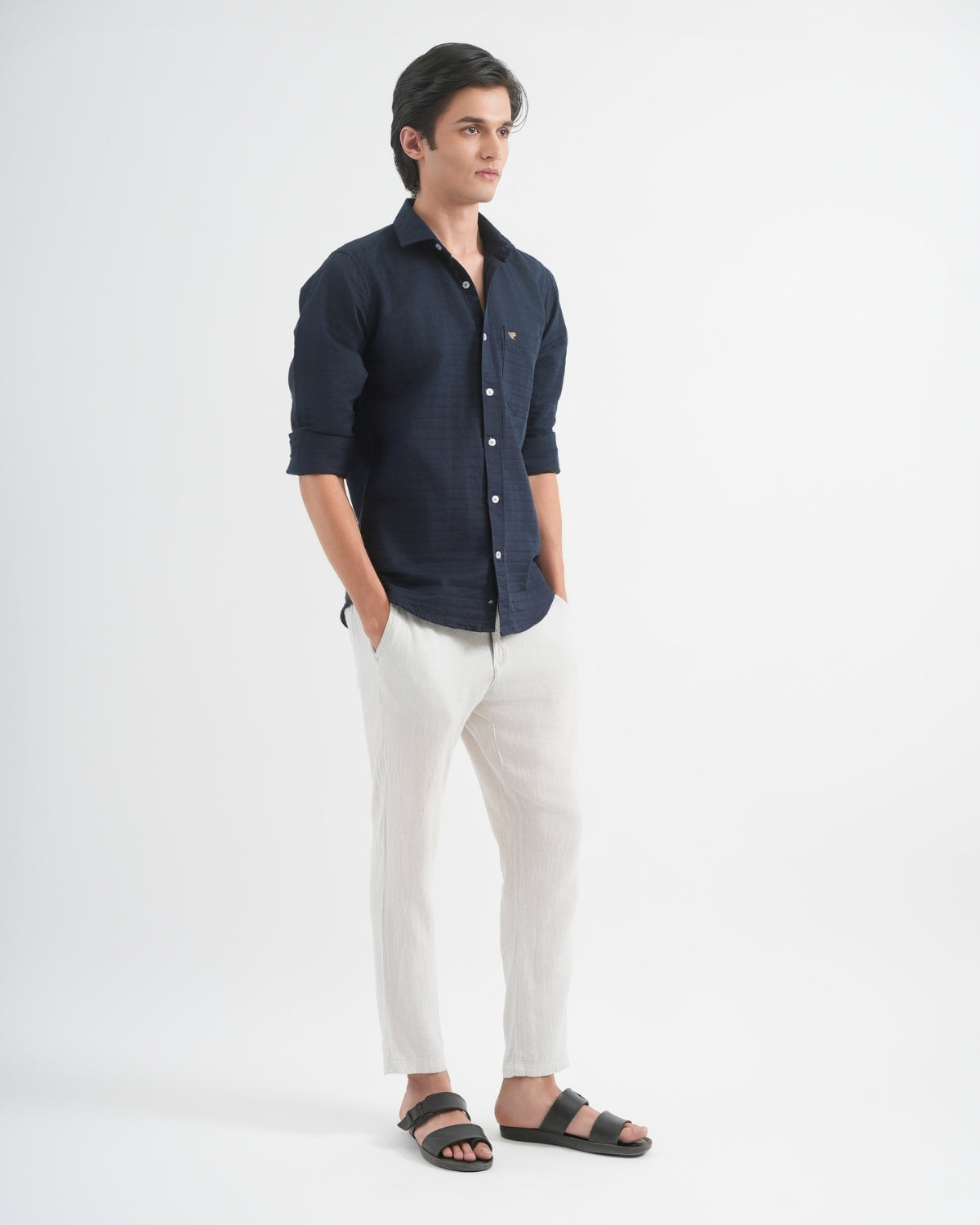 Man wearing a navy shirt and white pants on a white background