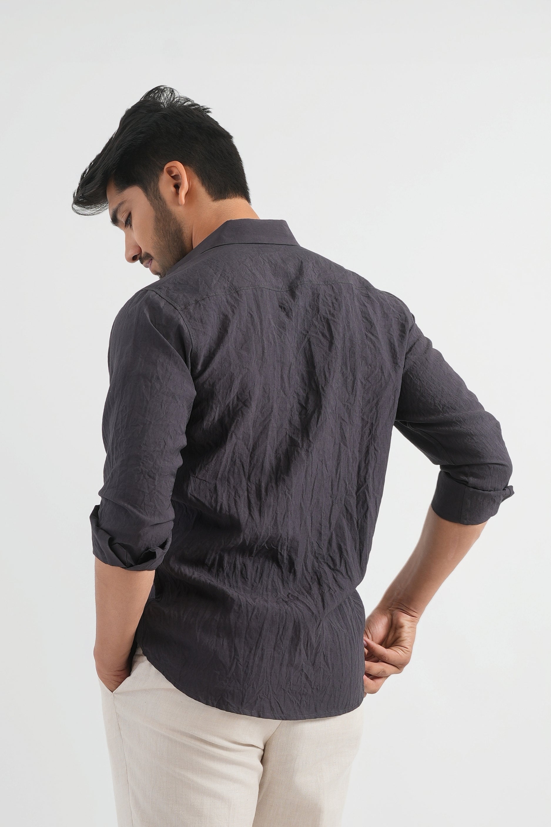 Man wearing a dark gray shirt and beige pants against a white background