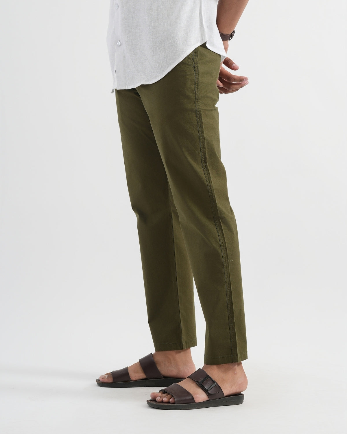 Person wearing olive green pants and brown sandals on a white background