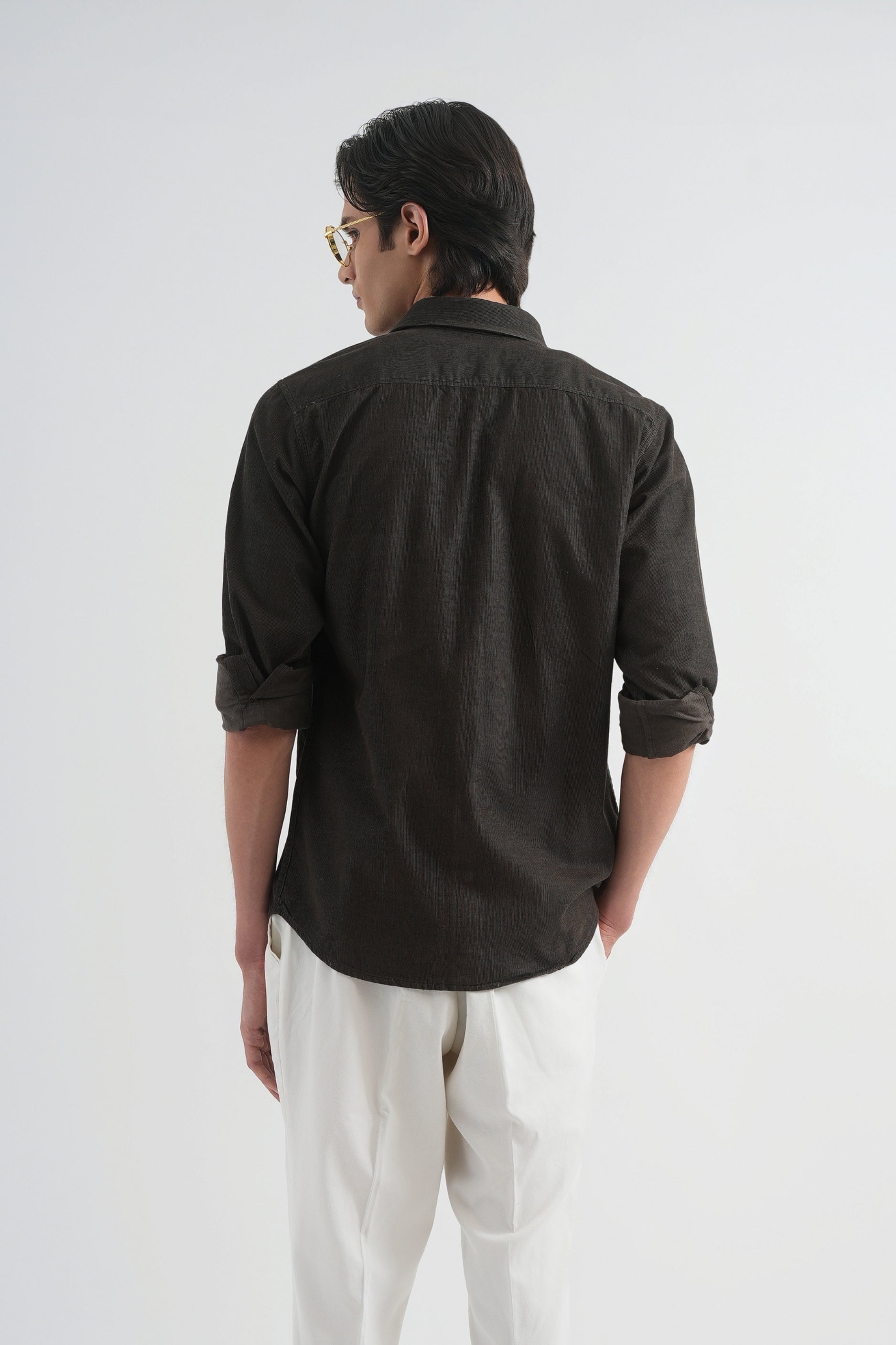 Man wearing a dark shirt, white pants, and brown shoes on a white background