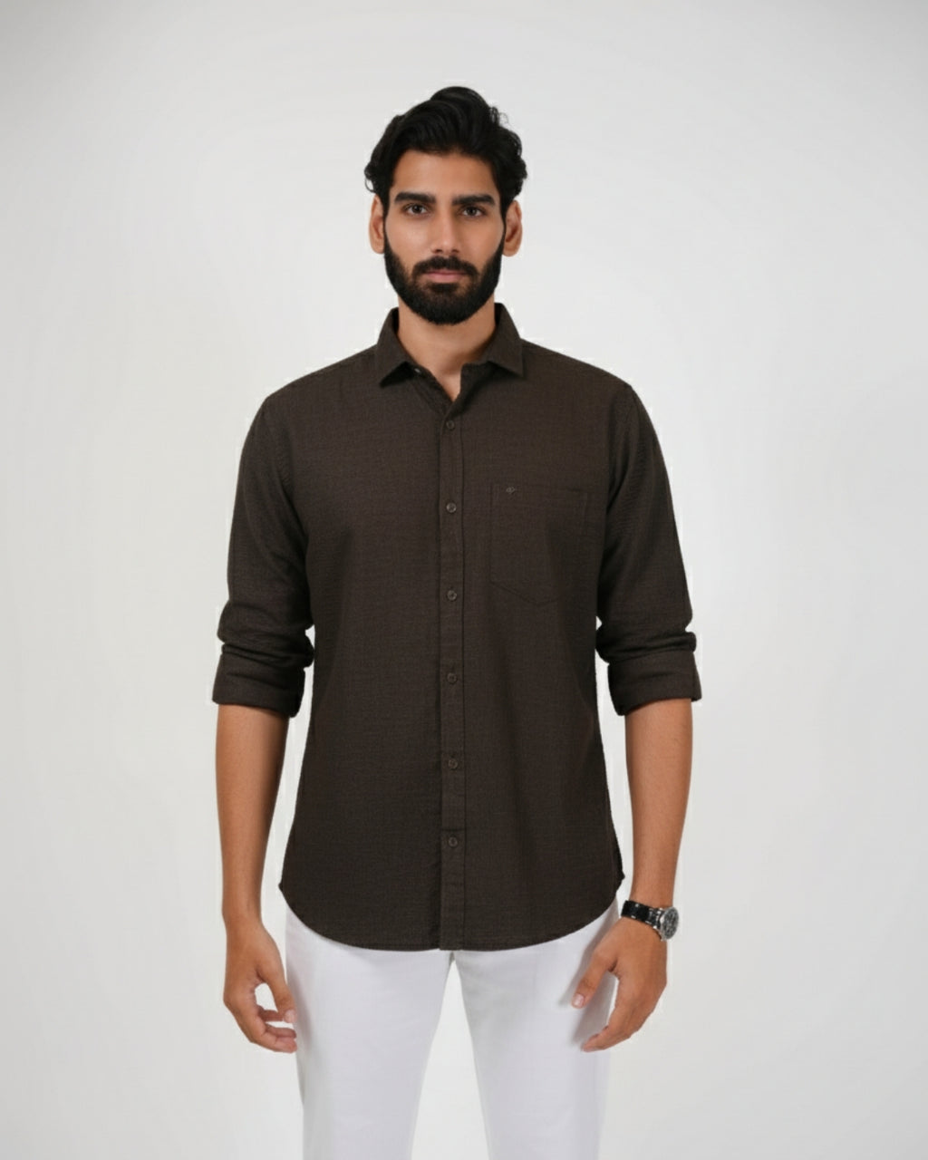 Man wearing a brown shirt and white pants on a plain background