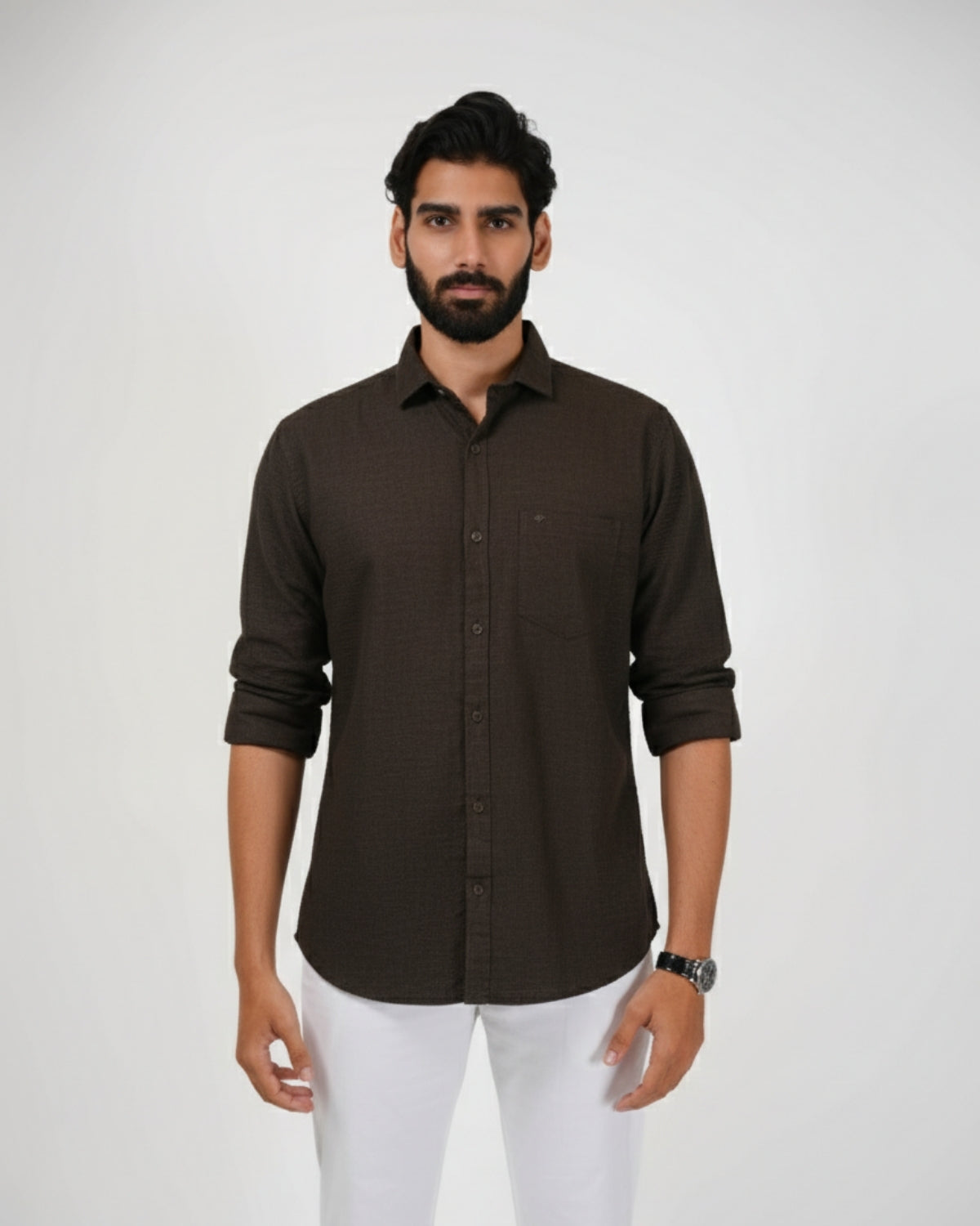 Man wearing a brown shirt and white pants on a plain background