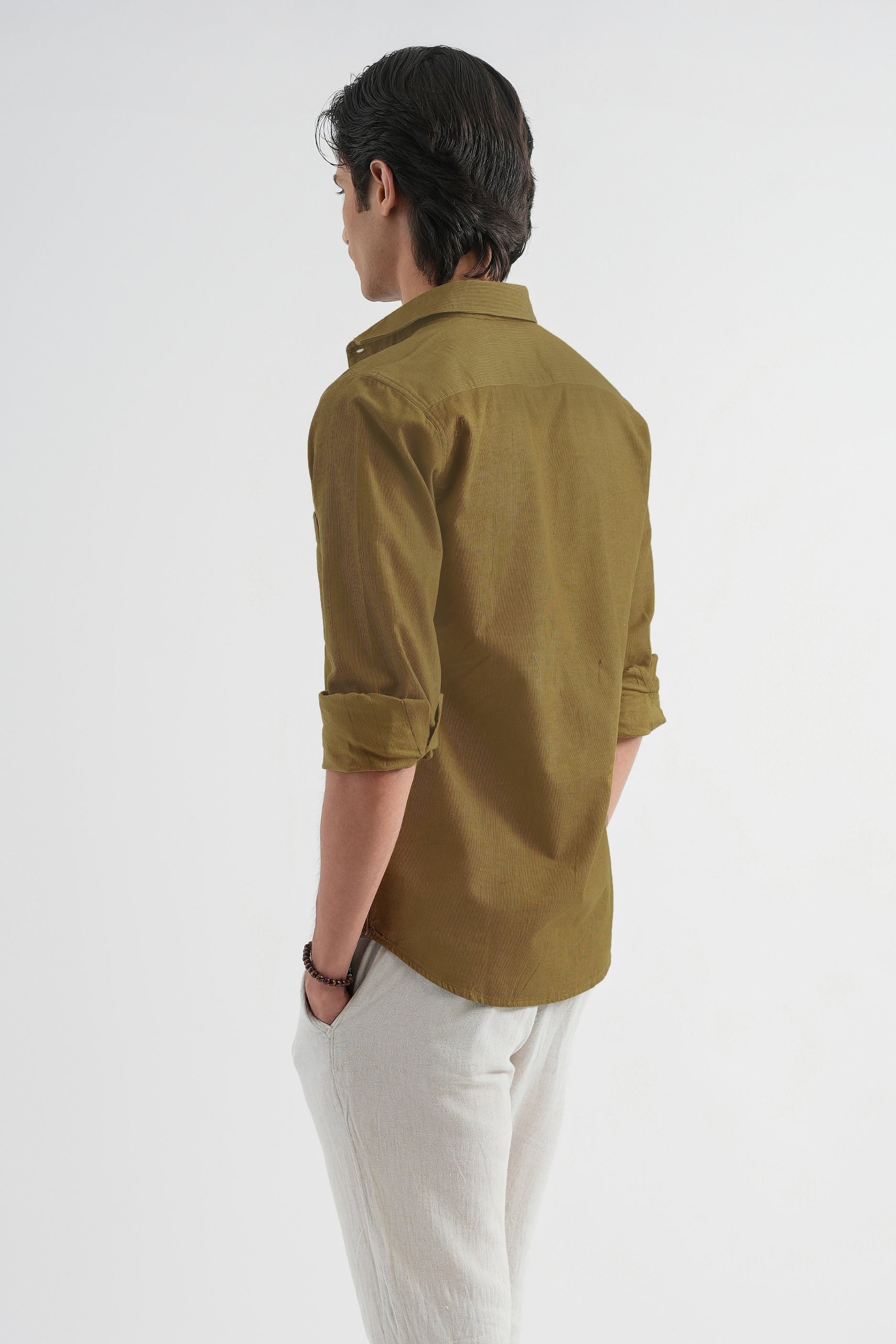 Person wearing a brown shirt and white pants on a white background