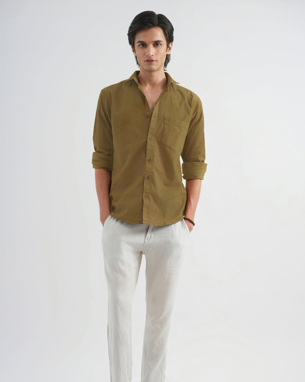 Man wearing a green shirt and white pants on a plain background