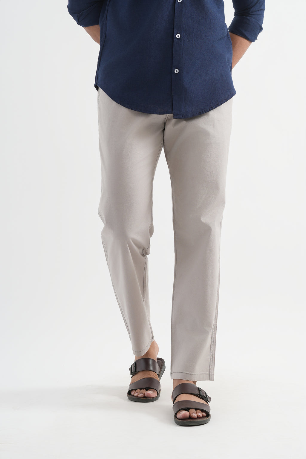 Person wearing a navy shirt and light gray pants on a white background