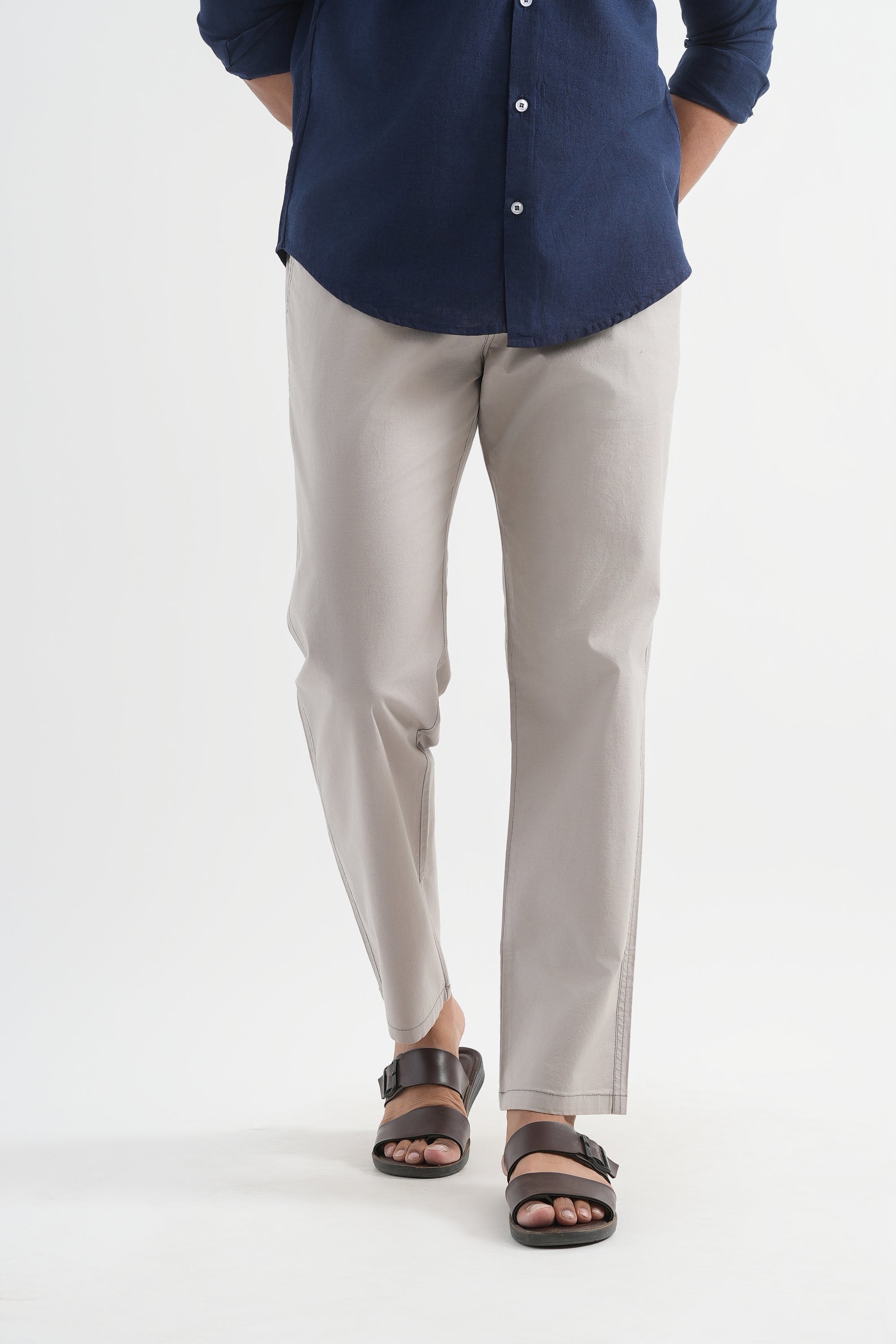 Person wearing a navy shirt and light gray pants on a white background