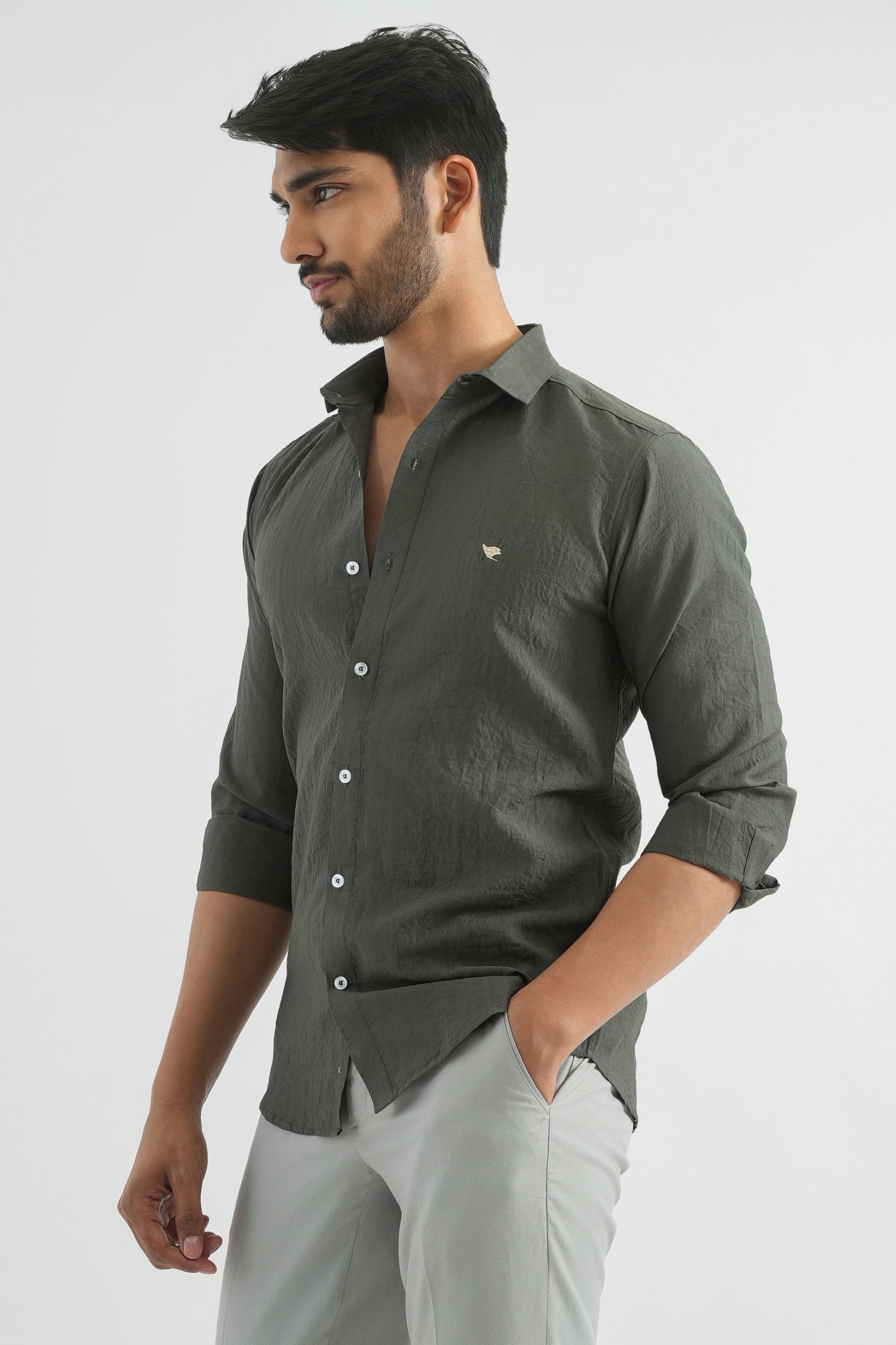 Man wearing a dark green shirt with rolled-up sleeves on a white background