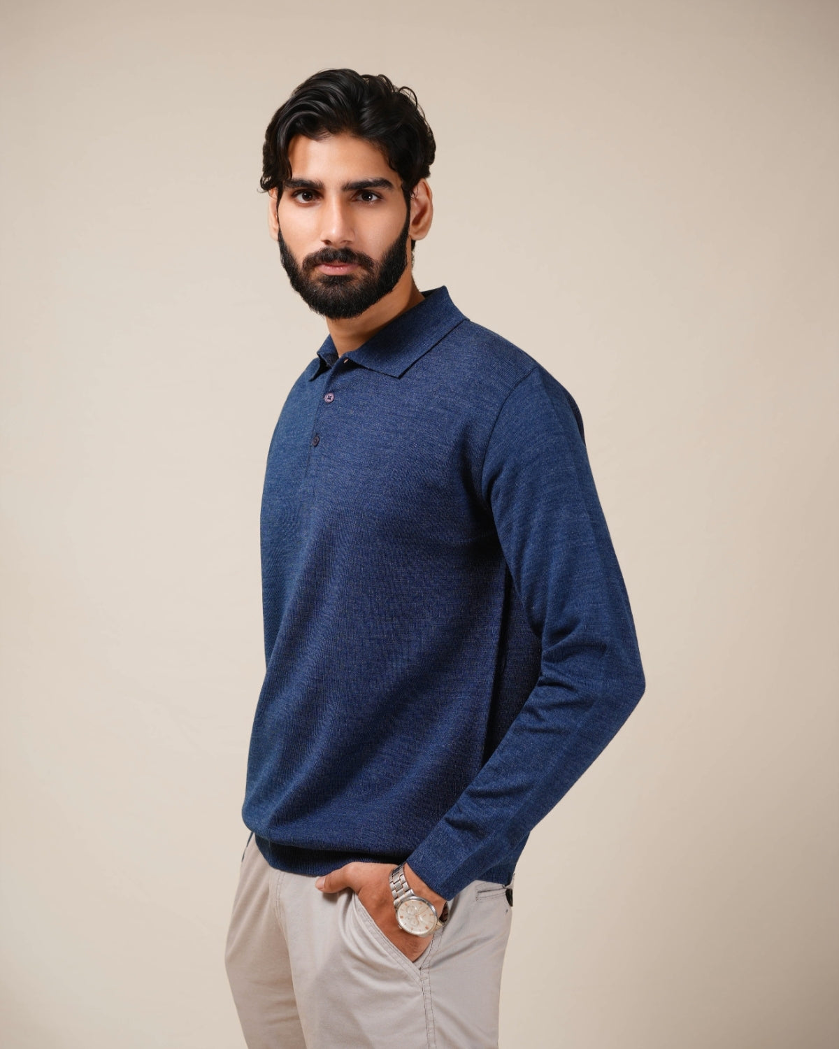 Man wearing a blue long-sleeve shirt against a beige background