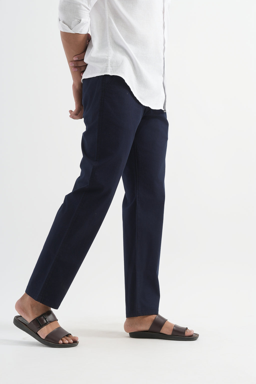 Person wearing navy pants and a white shirt on a white background