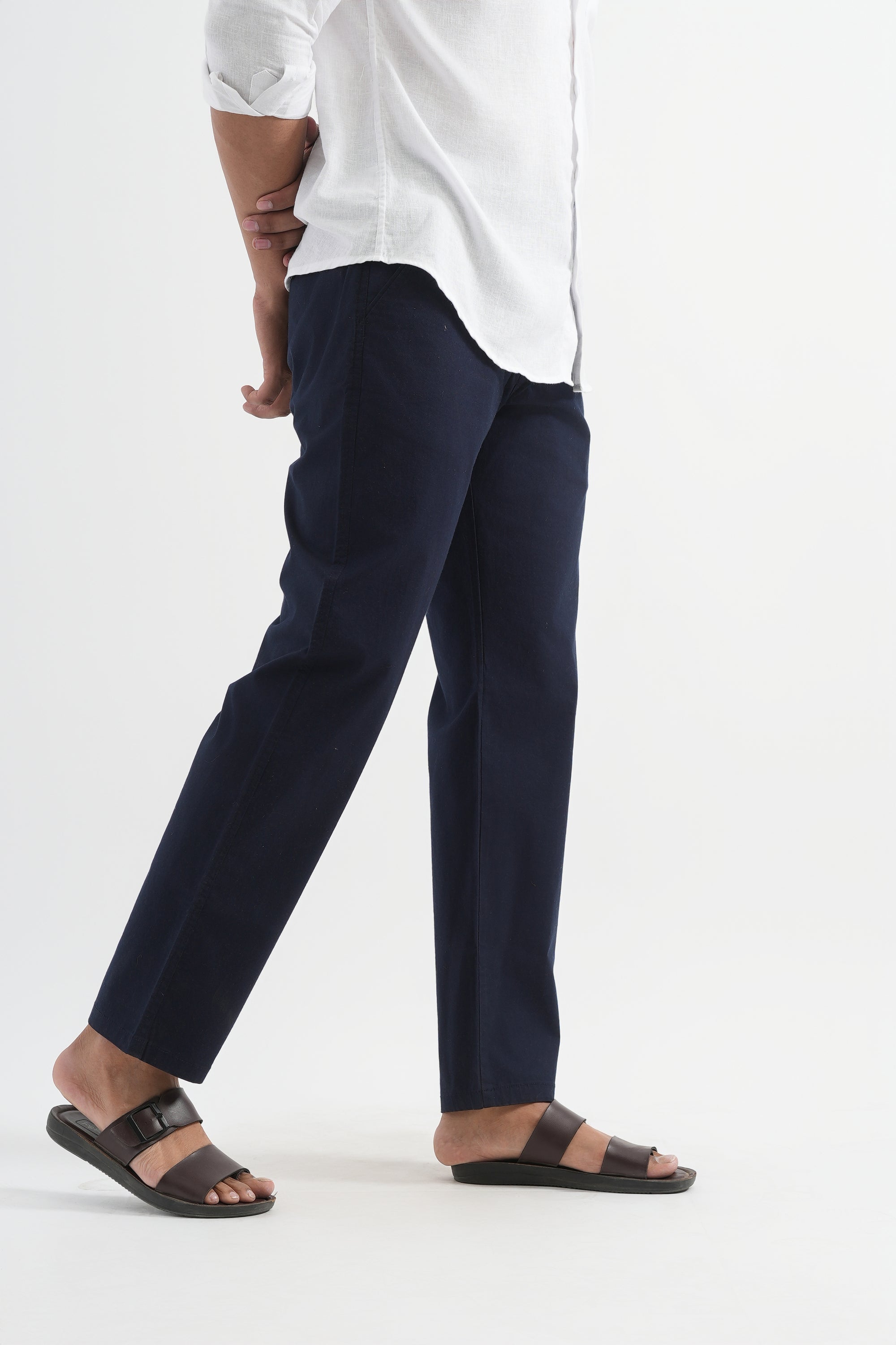 Person wearing navy pants and a white shirt on a white background