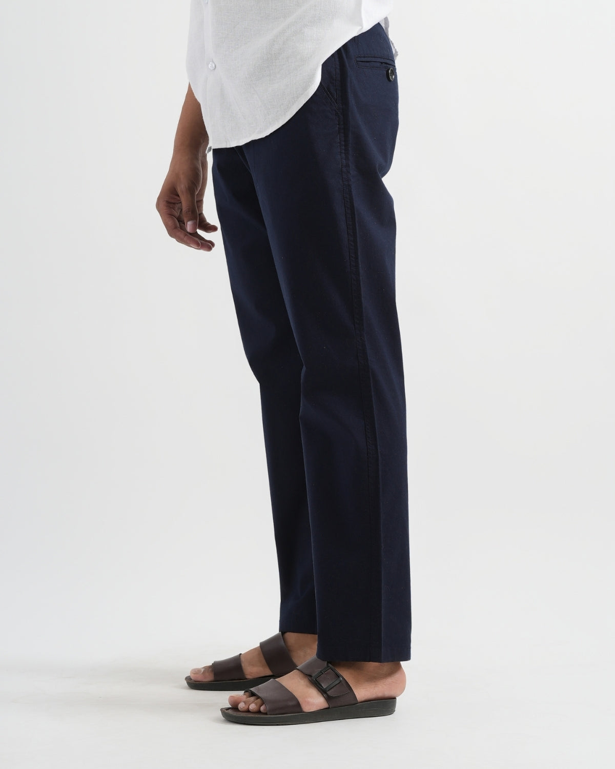 Person wearing navy pants and a white shirt on a white background