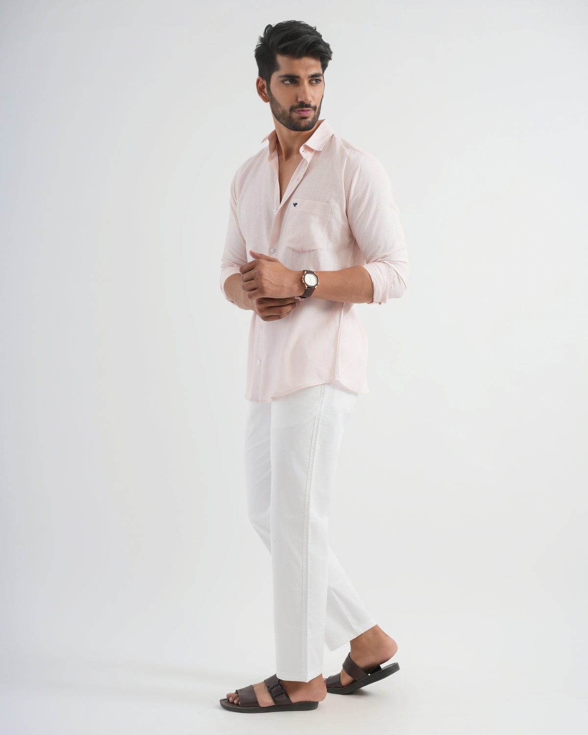 Man wearing a light pink shirt and white pants on a white background