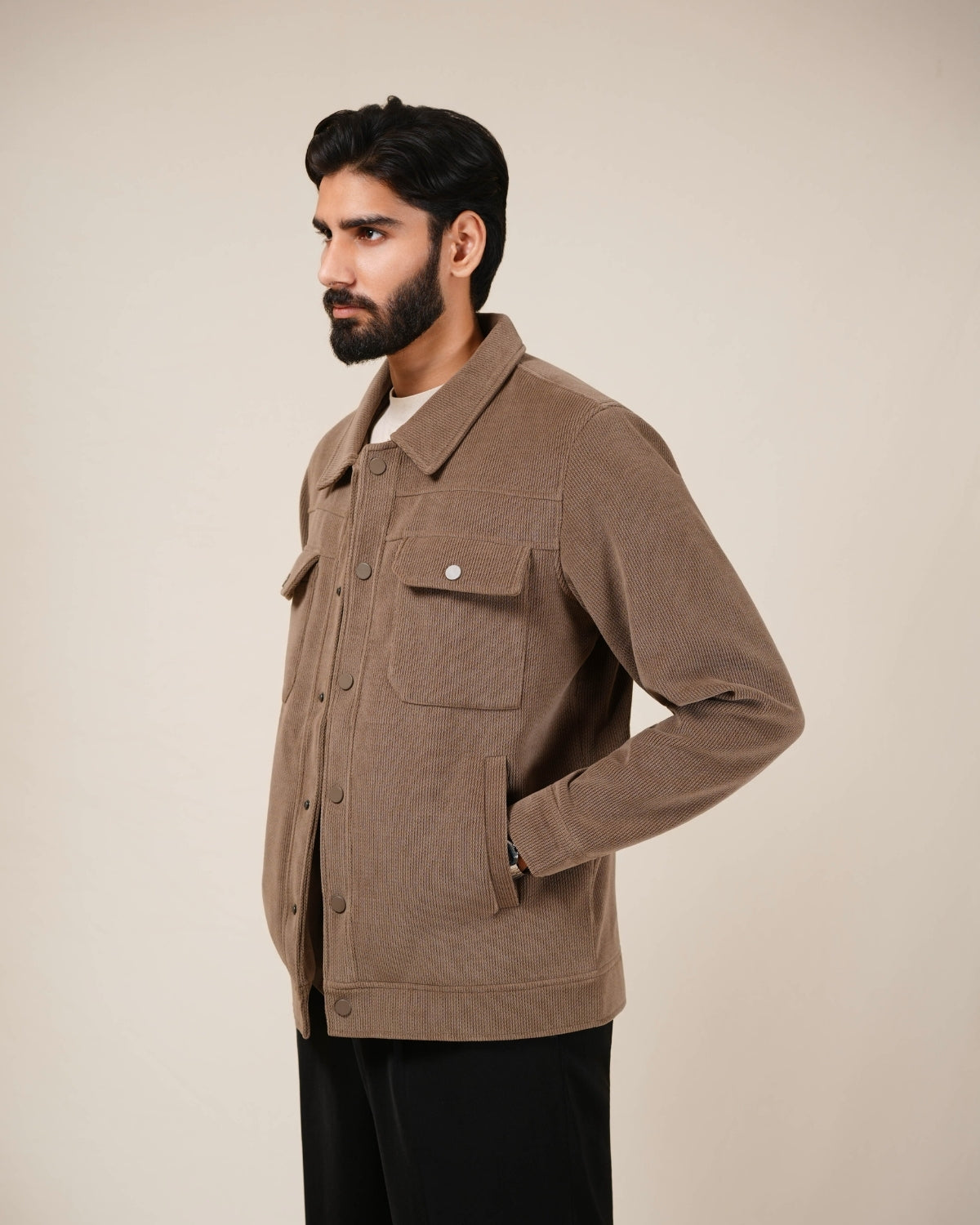 Close-up of a brown corduroy jacket with buttons and a pocket.