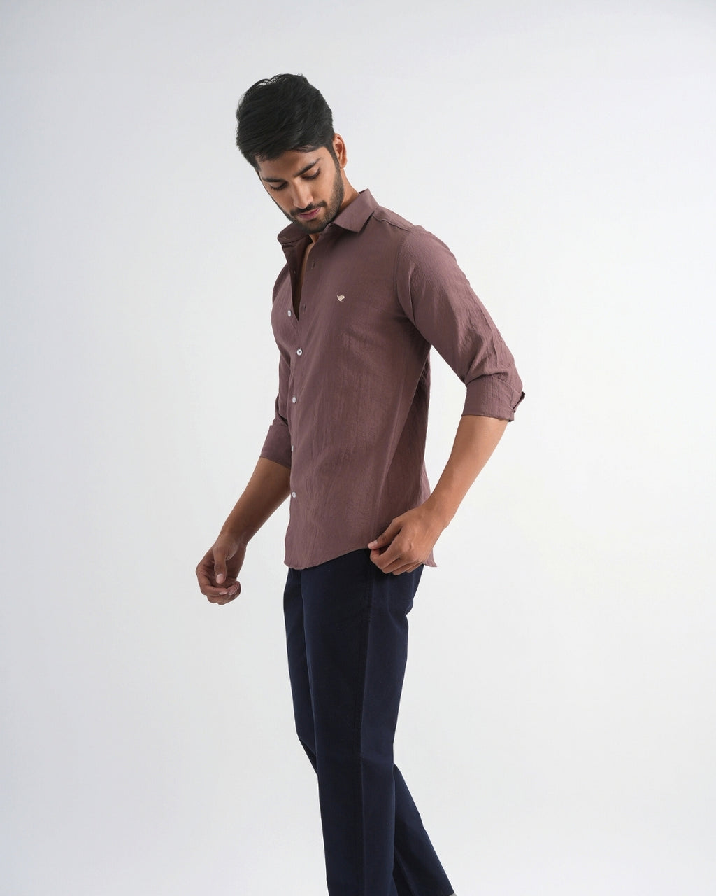 Man wearing a brown shirt and dark pants on a white background