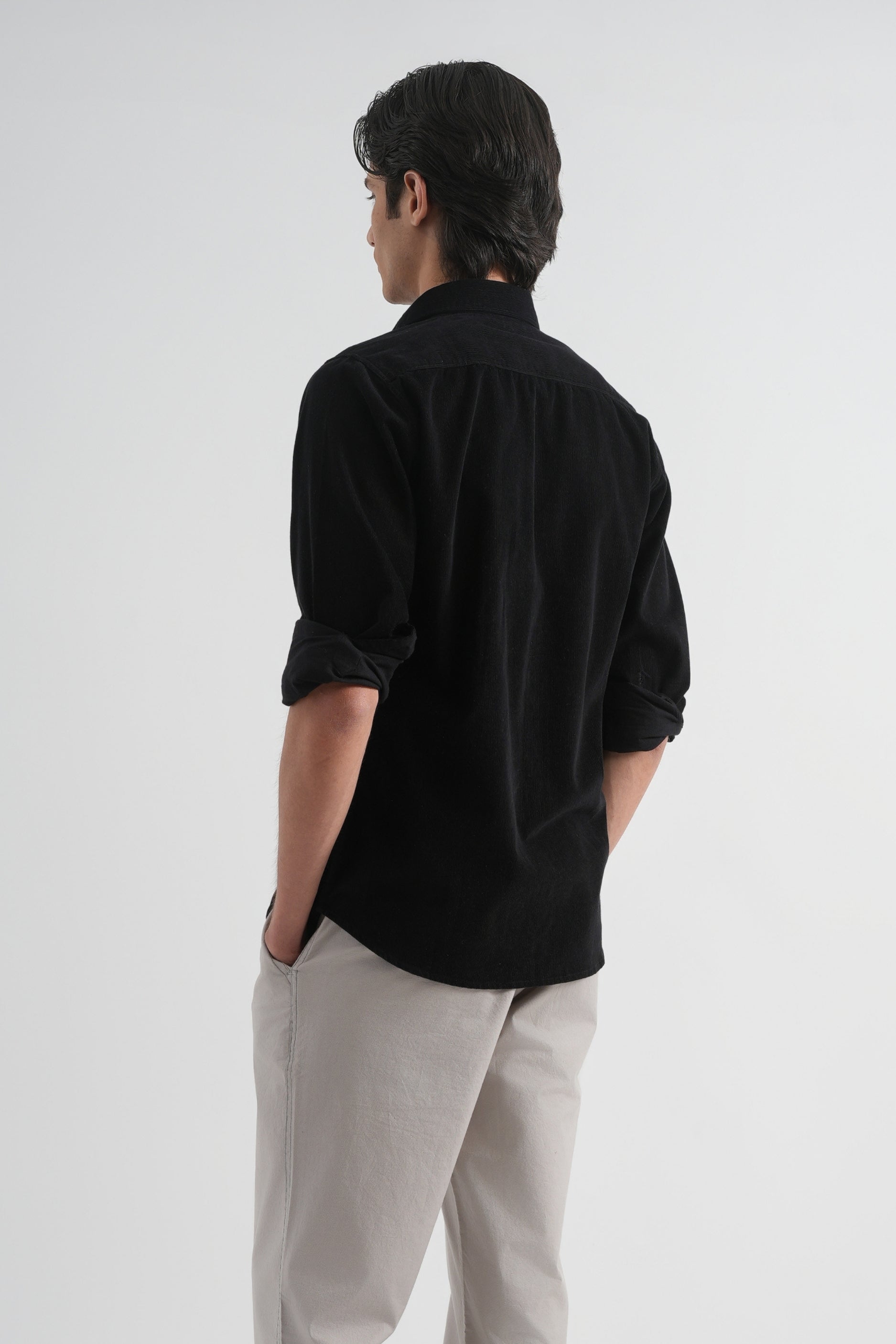 Man wearing a black shirt and beige pants on a white background