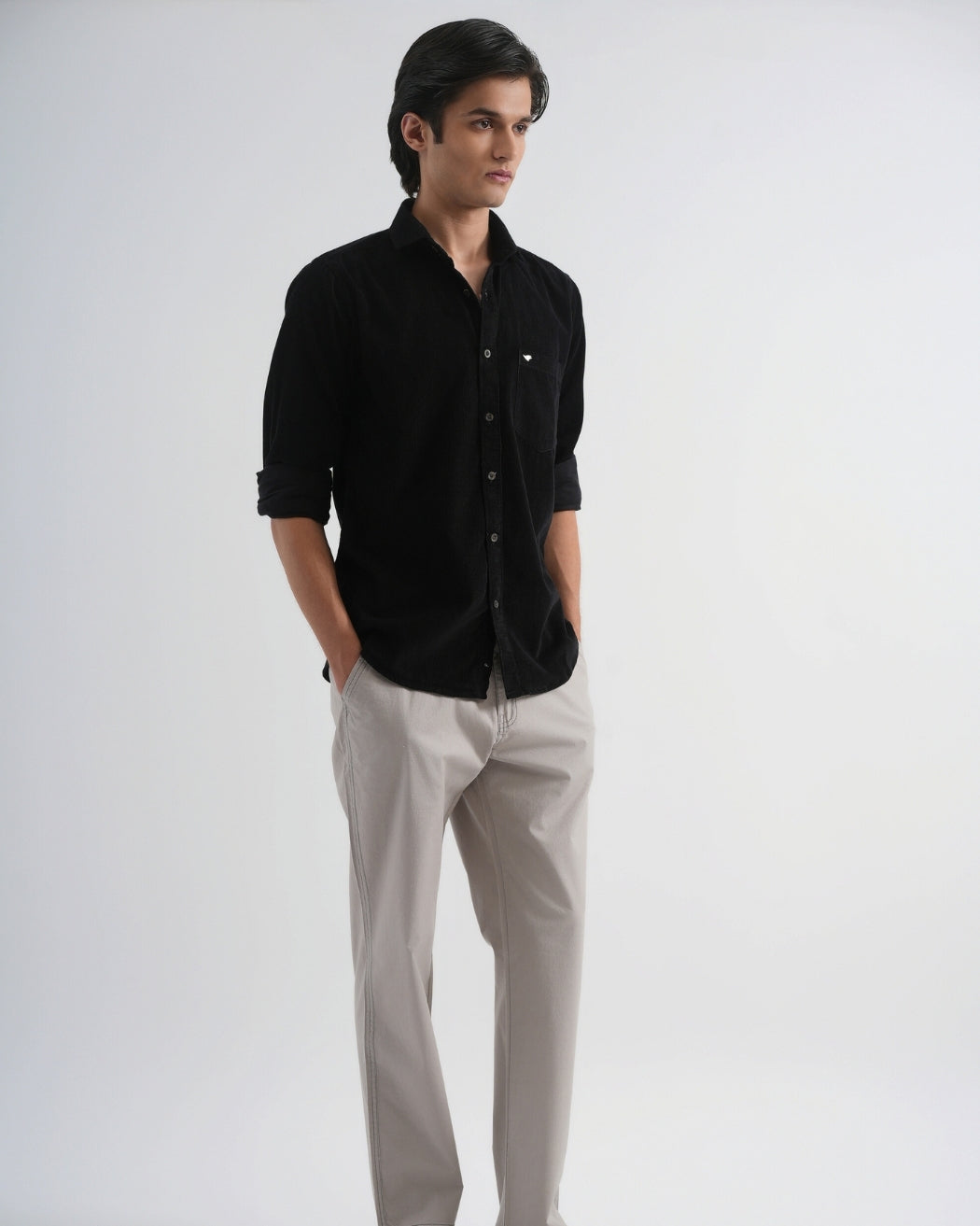 Man wearing a black shirt and light gray pants on a white background