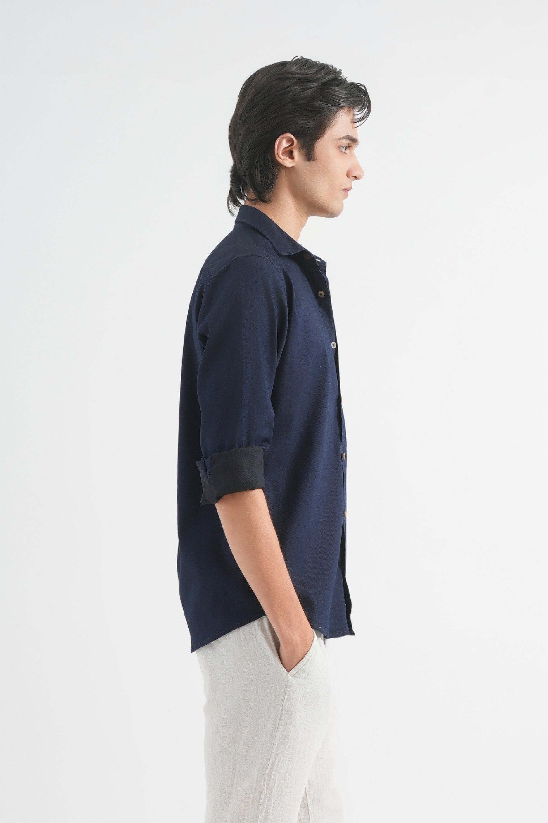Person wearing a navy blue shirt and white pants on a white background
