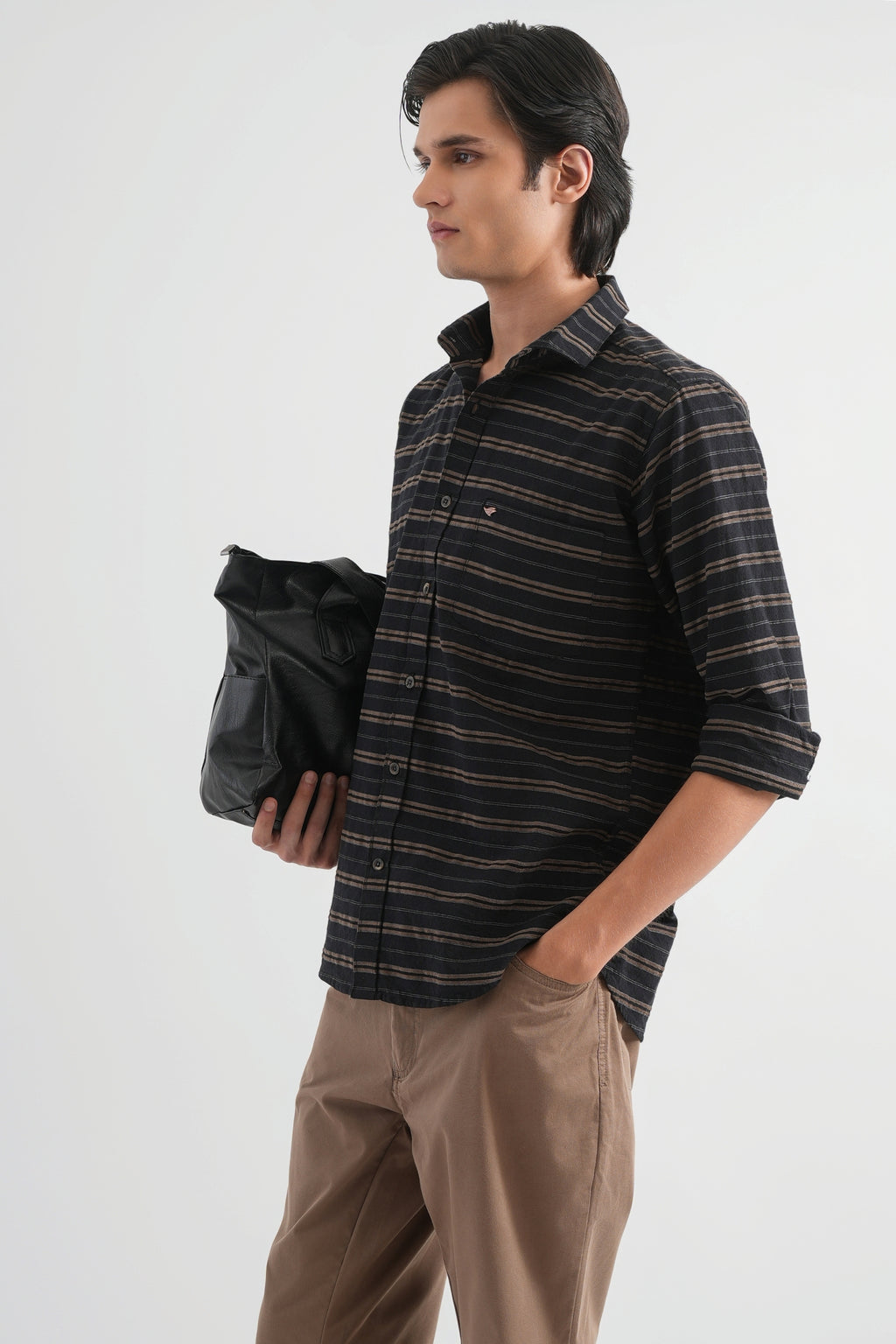 Man wearing a striped shirt and holding a black bag on a white background