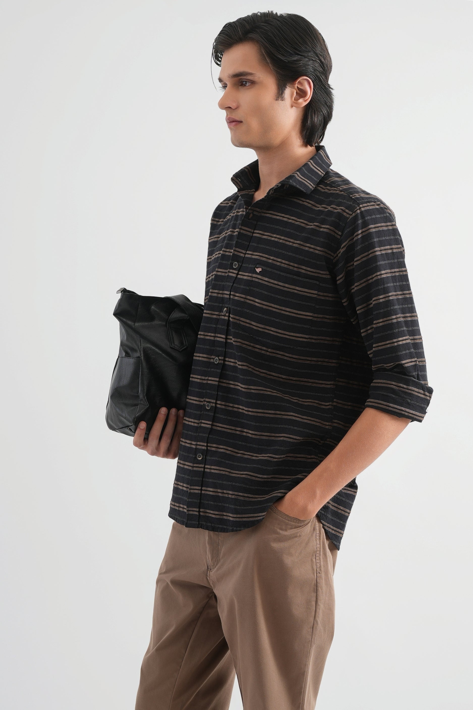 Man wearing a striped shirt and holding a black bag on a white background