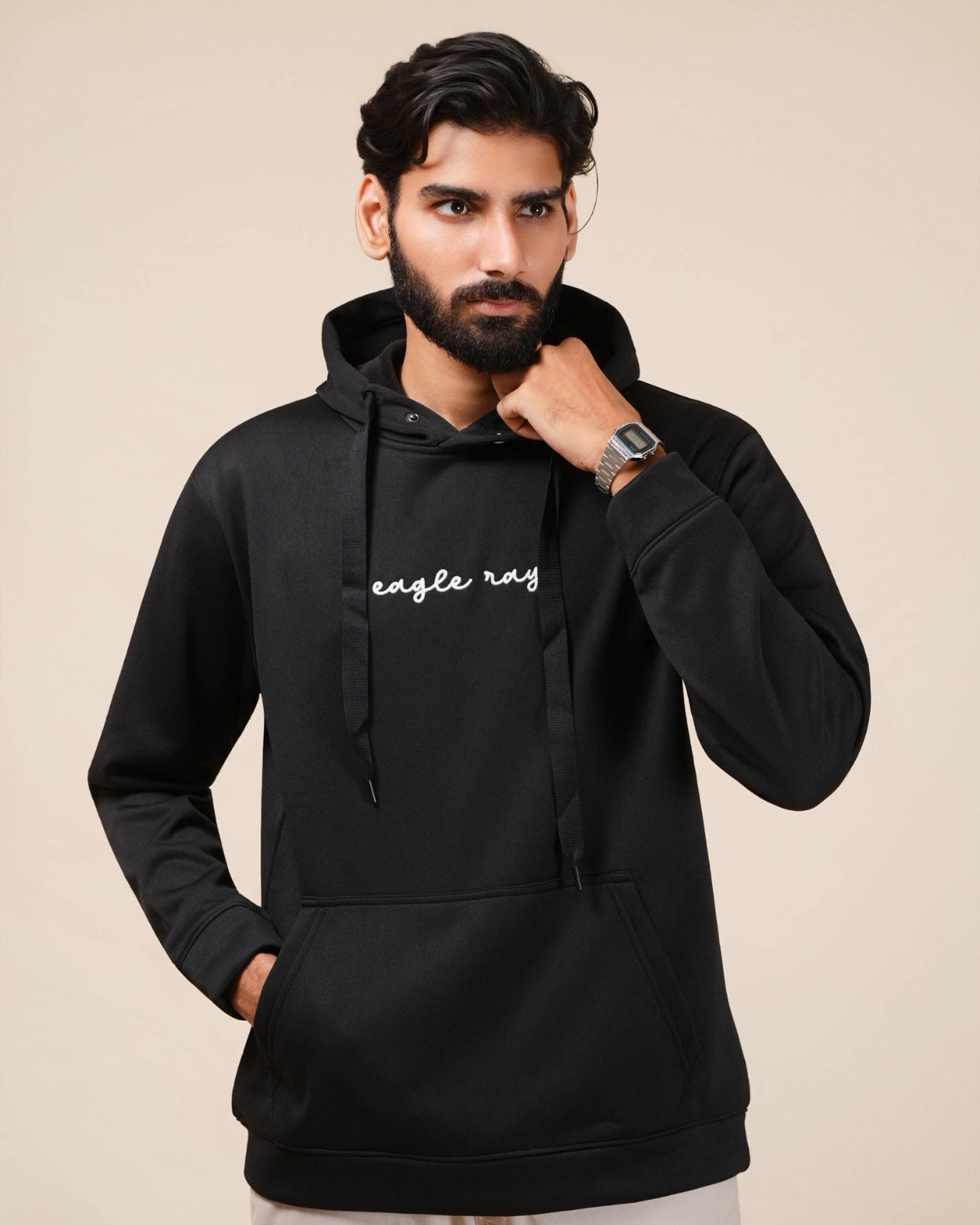 Close-up of a black sweatshirt sleeve with a brand logo on a beige background