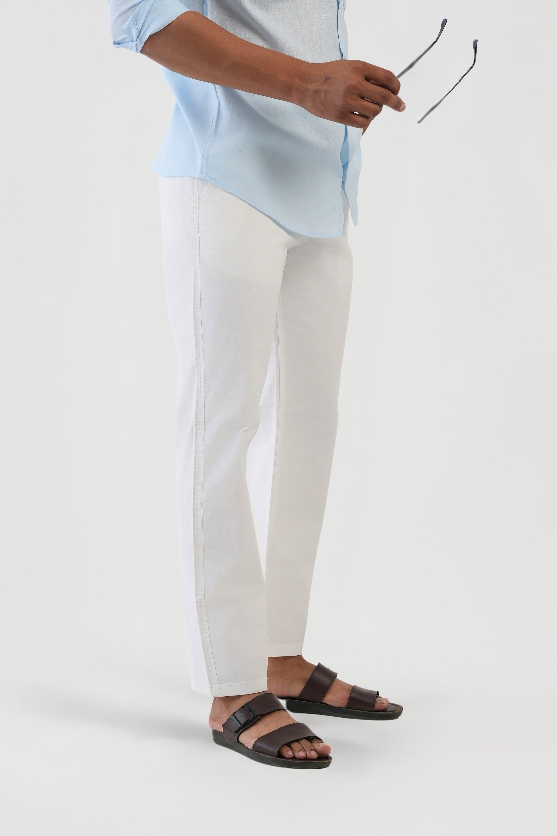 Person wearing a light blue shirt, white pants, and black sandals on a white background
