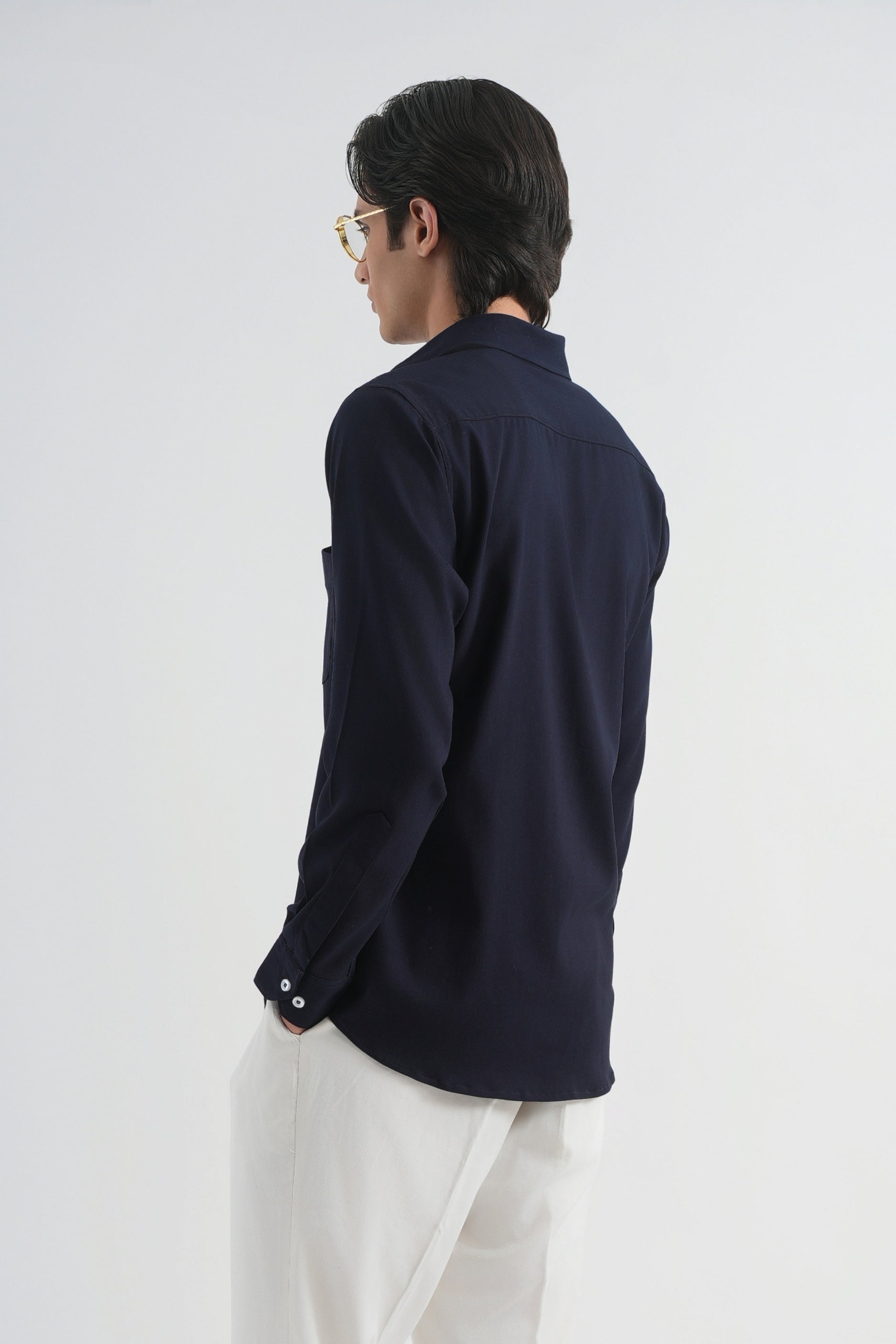 Person wearing a navy long-sleeve shirt and white pants on a white background
