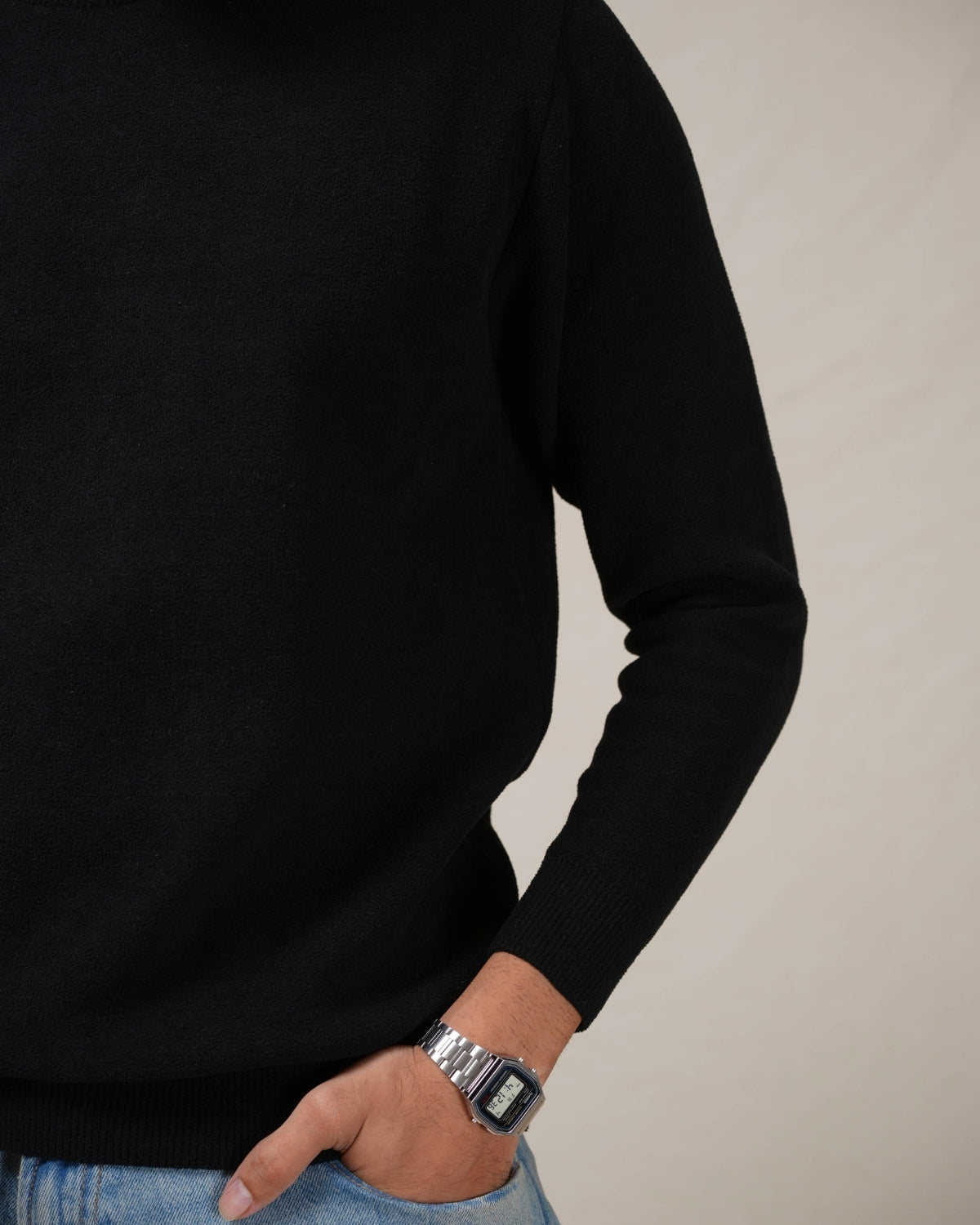 Person wearing a black sweater with a neutral background
