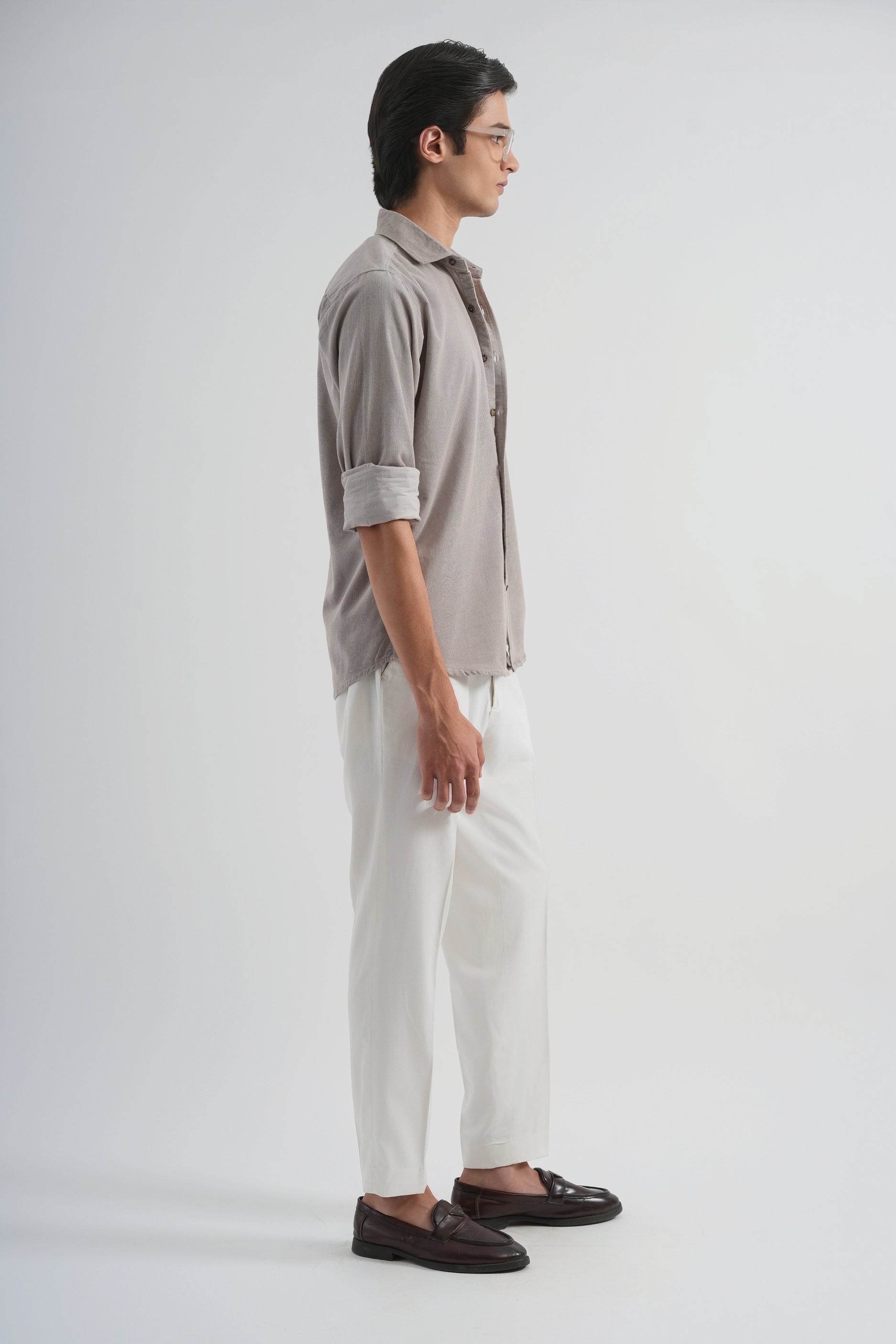 Man wearing a gray shirt, white pants, and brown shoes on a white background