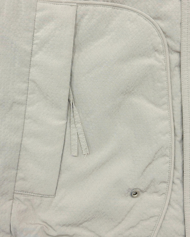 Close-up of a light gray corduroy jacket with a pocket and button detail.