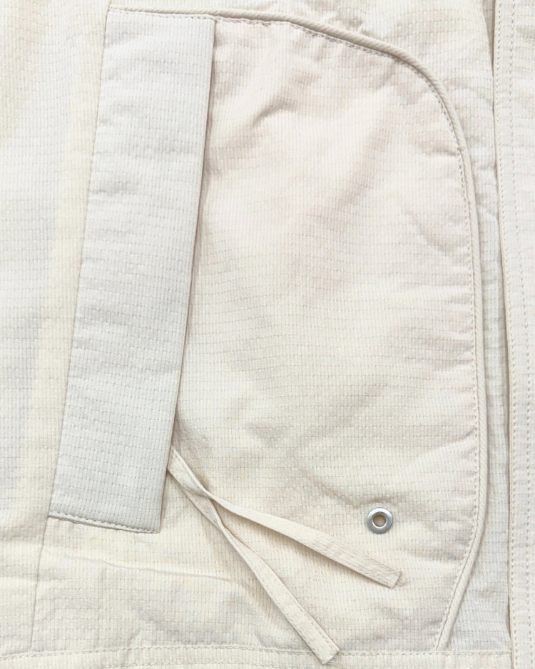 Close-up of a beige jacket with a button and sleeve detail