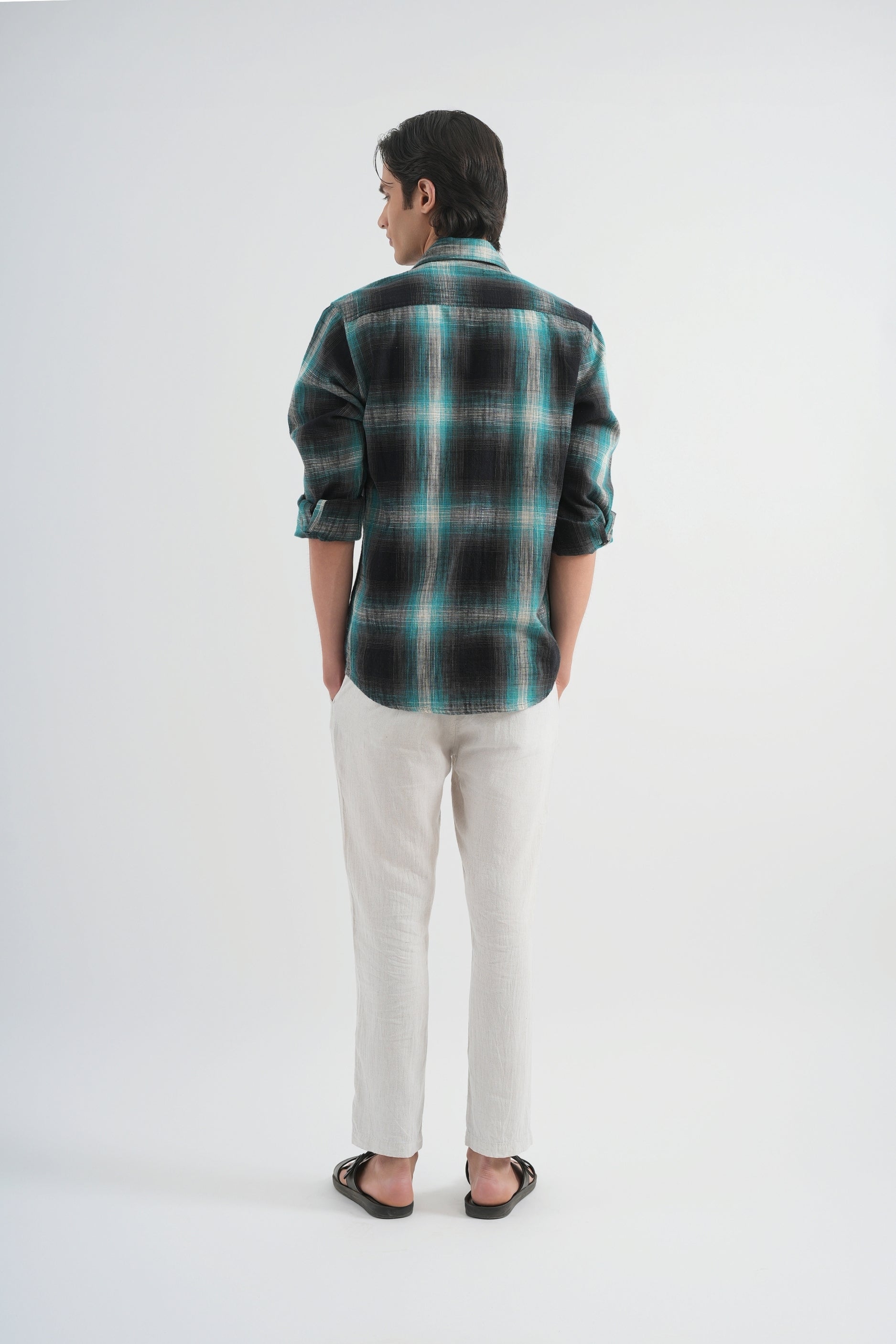 Person wearing a plaid shirt and white pants on a white background