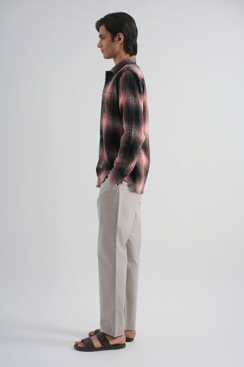 Man wearing a plaid shirt and beige pants on a white background
