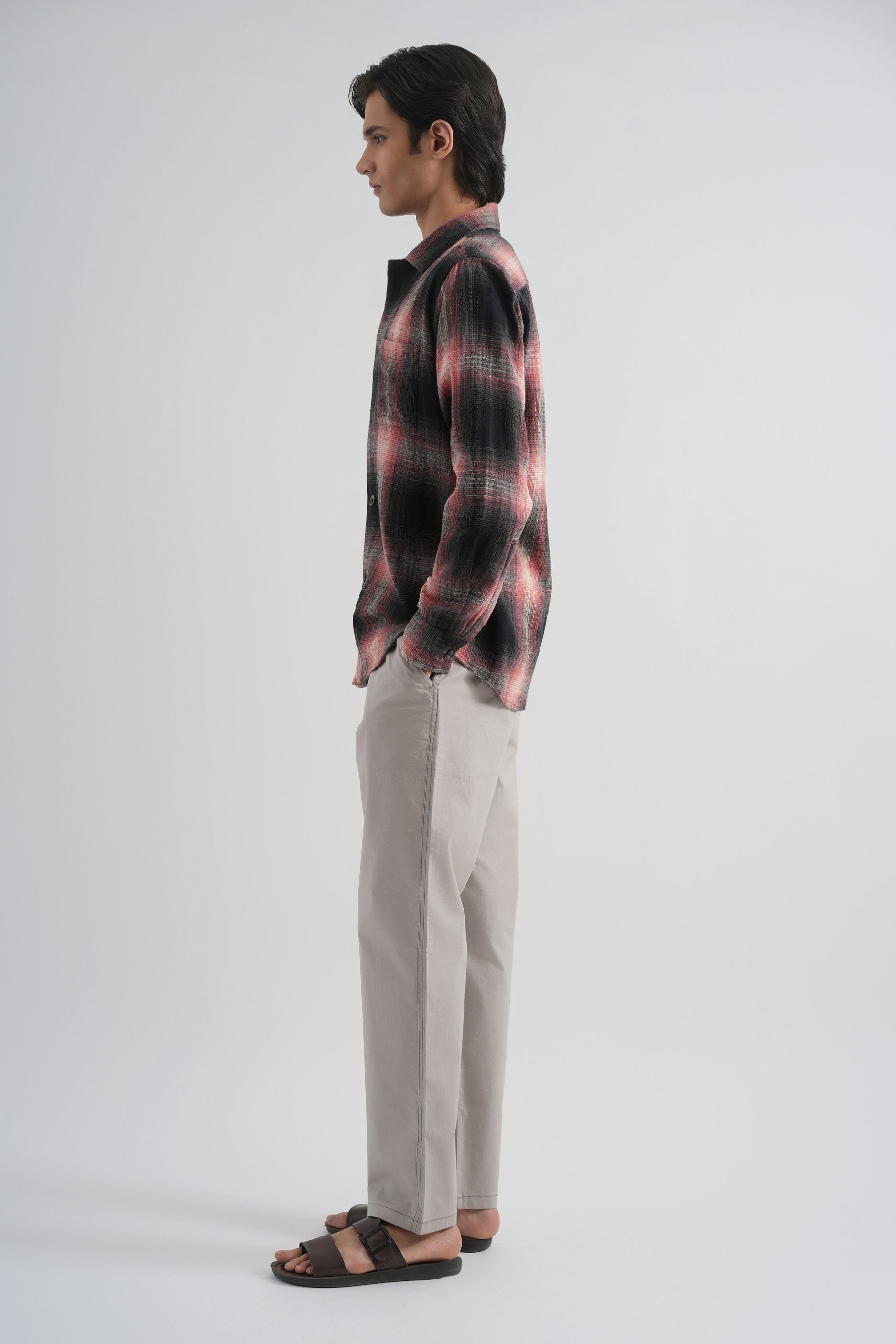 Man wearing a plaid shirt and beige pants on a white background